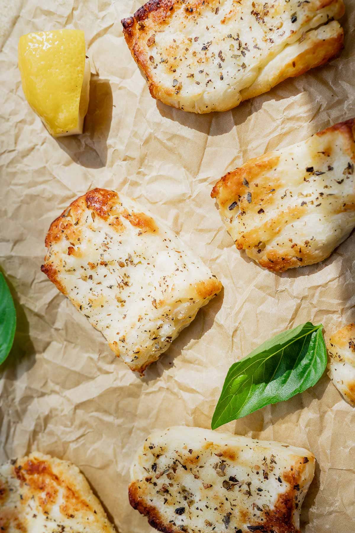 Sunlight hits slices of halloumi cheese resting on wrinkled parchment paper.