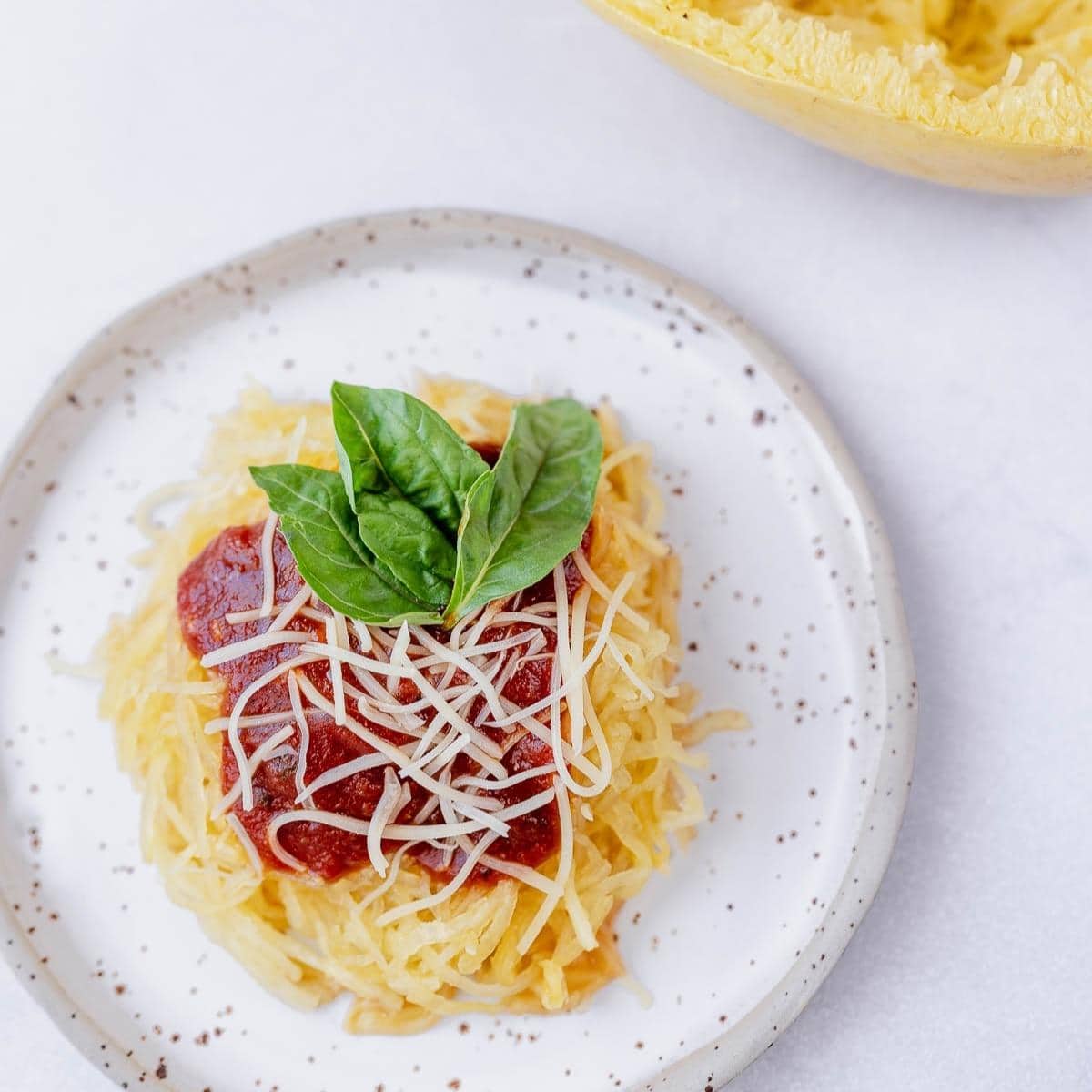 Overhead shot of Air Fryer spaghetti squash on a stoneware plate with marinara, parmesan and fresh basil on top.