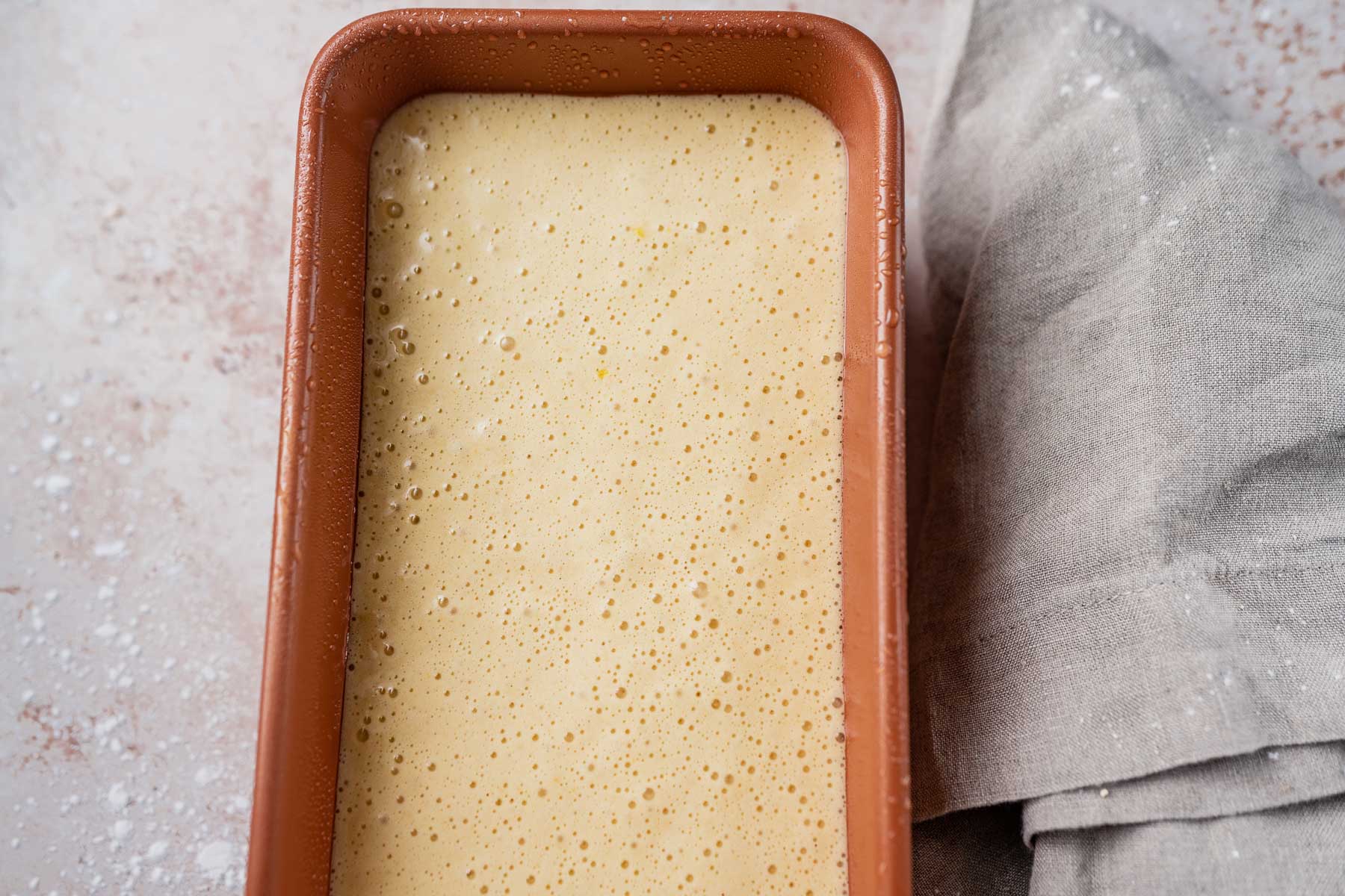 A copped bread pan filled with a light yellow mixture.