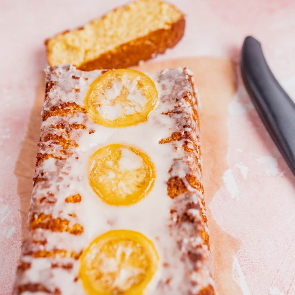 A loaf cake topped with a white glaze and candied lemons.