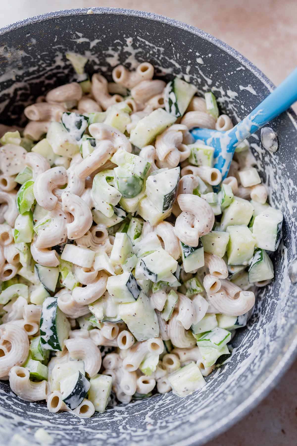 Gluten-free macaroni salad in a large bowl with a blue spoon.