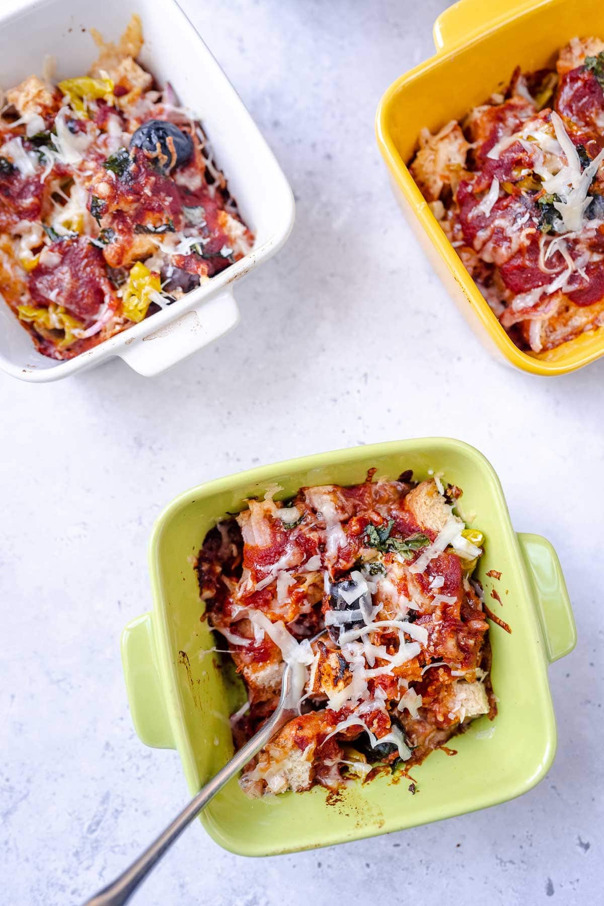 A pizza bowl in a green ramekin with a fork.