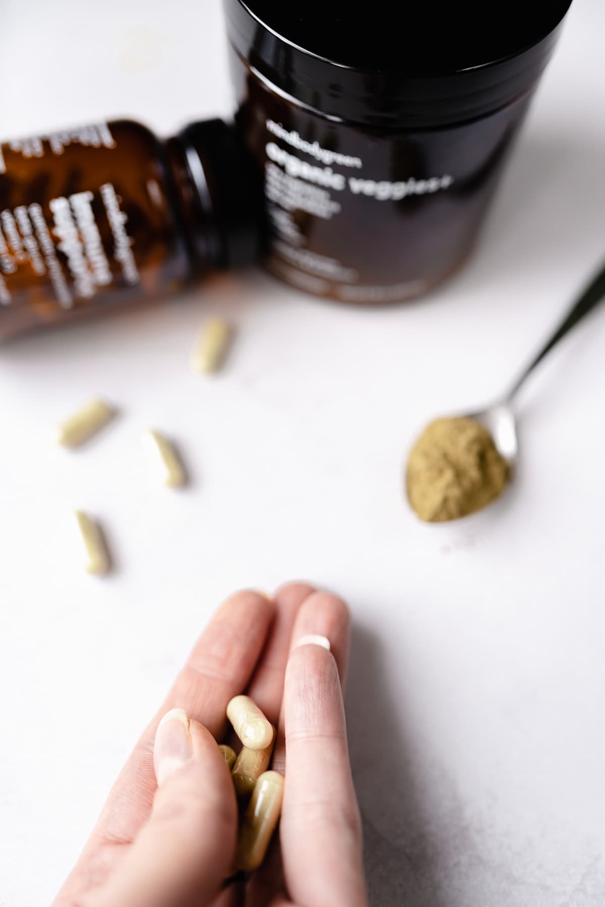 A hand holds some tan supplement capsules.