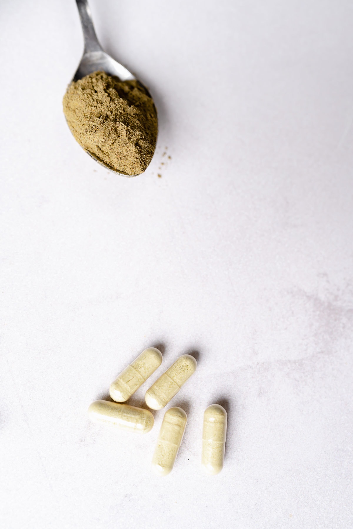 Tan powder and capsules rest on a white background.