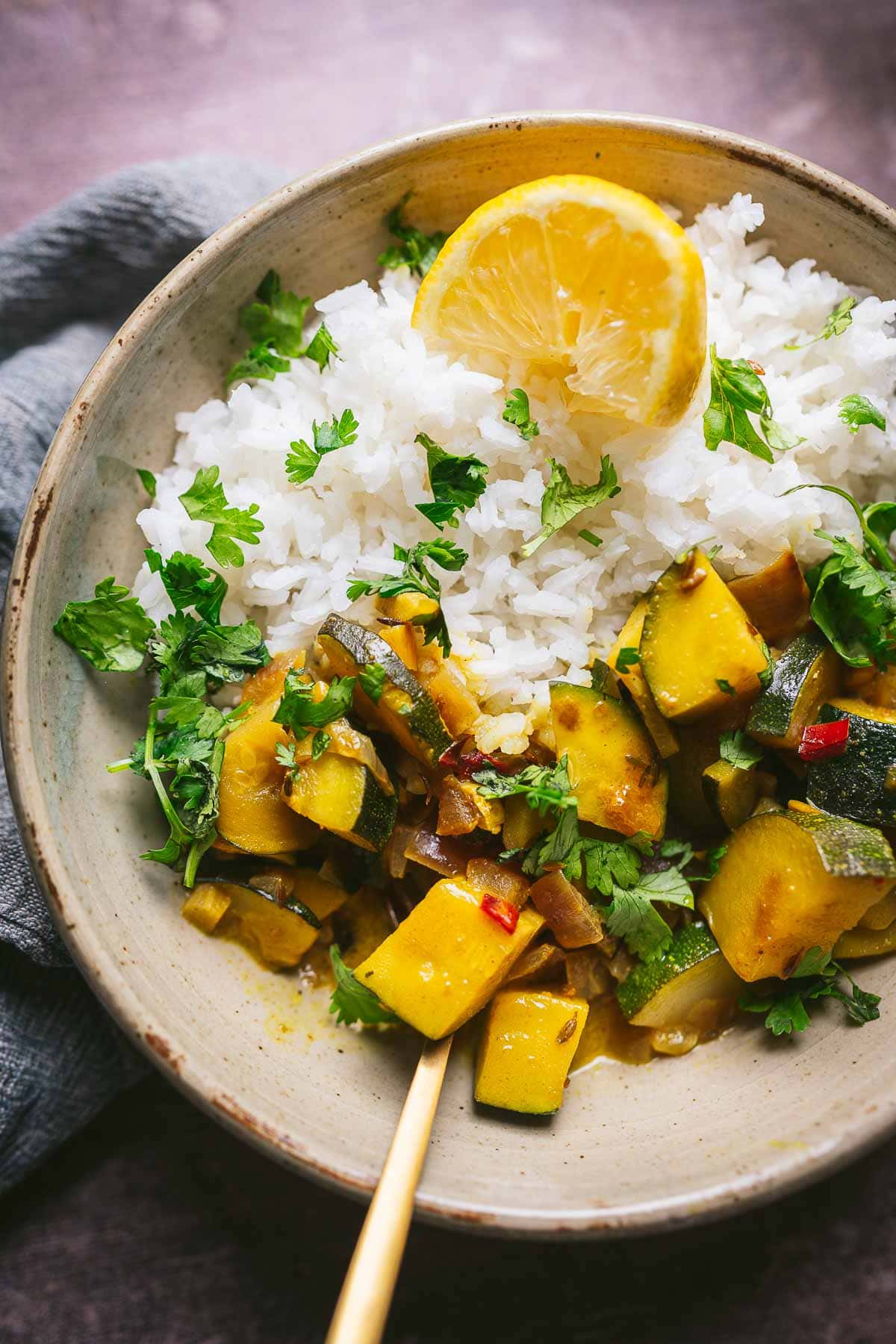 Close shot of yellow zucchini curry served over rice and garnished with cilantro.