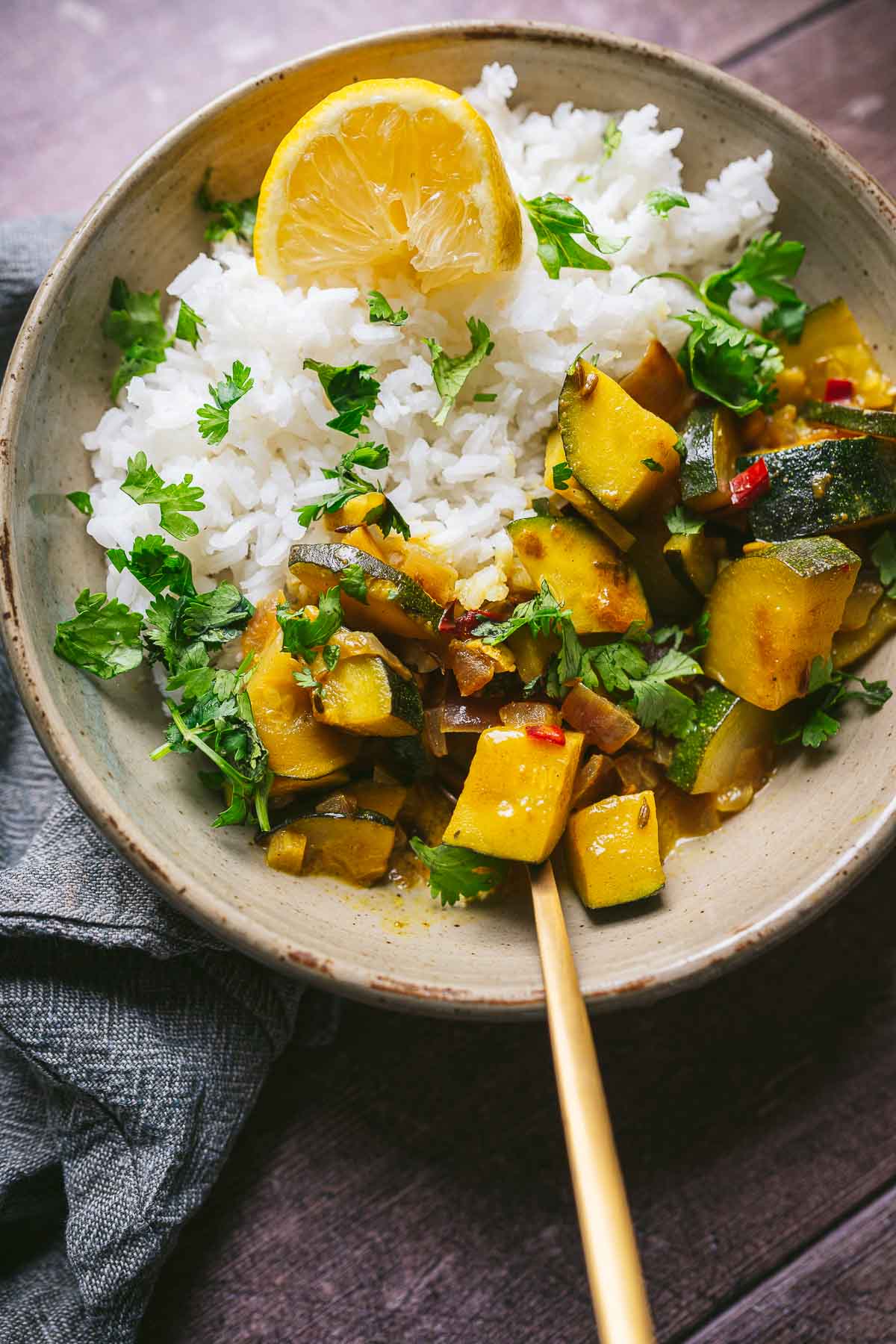Zucchini curry over rice in a large gray ceramic bowl.
