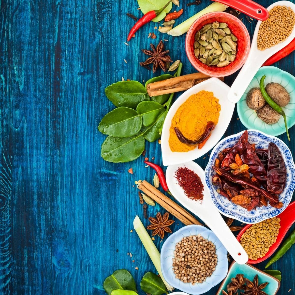 Various spices resting on a blue wooden board.