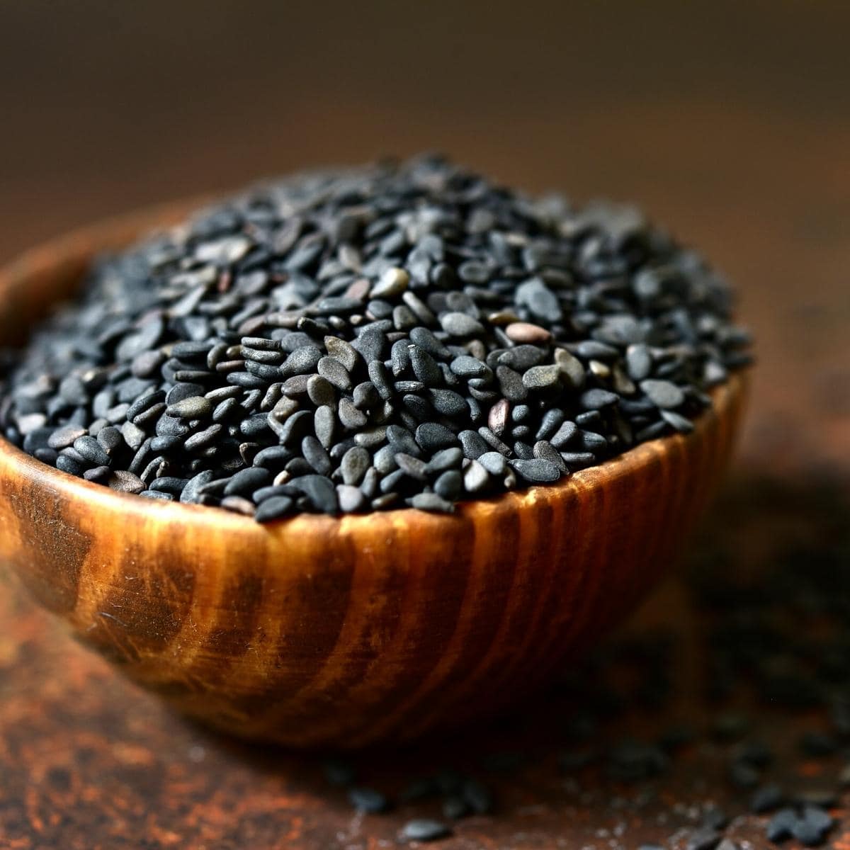 A small wood bowl of black sesame seeds.