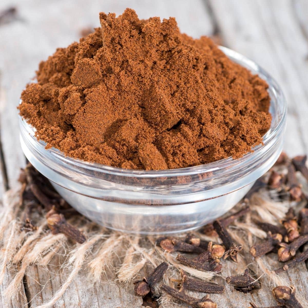 A small glass dish filled with ground cloves.