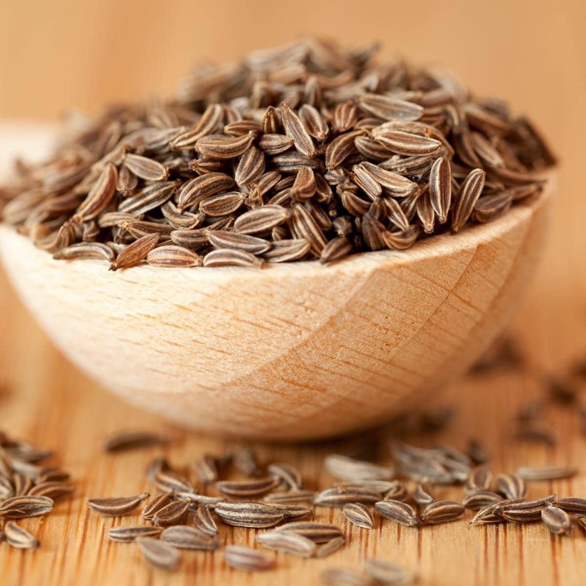 Close shot of cumin seeds in a wooden bowl.