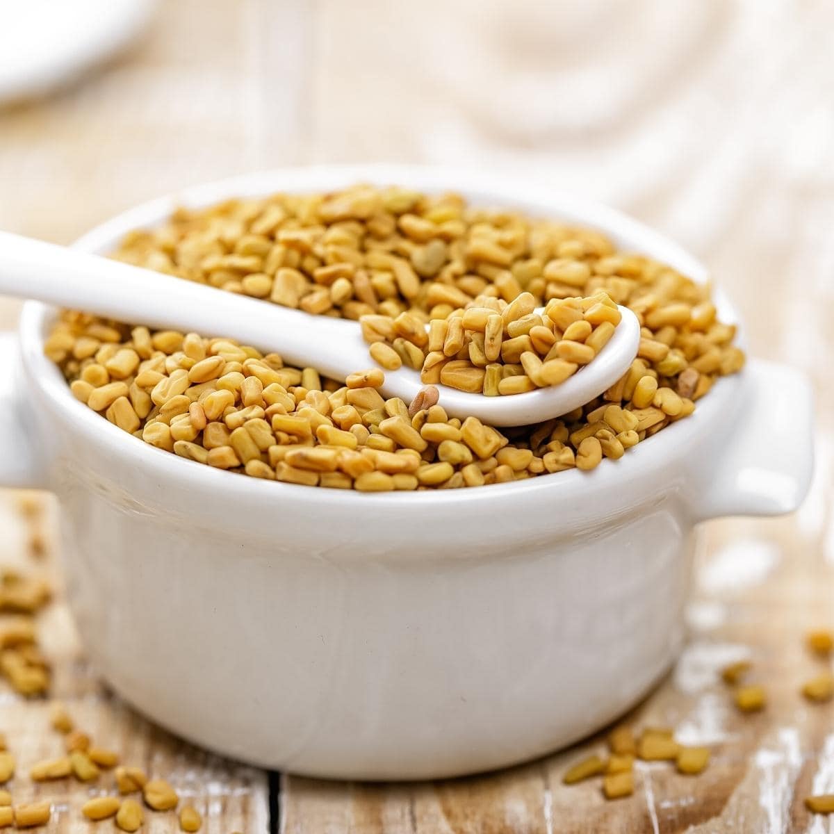 A white dish filled with fenugreek seeds.