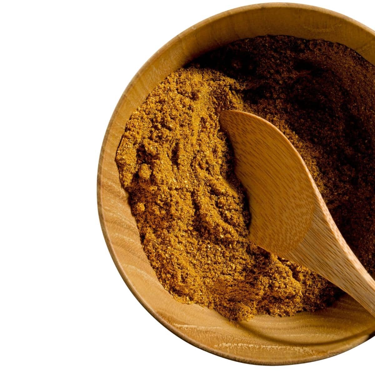 A small wooden bowl filled with garam masala and a wooden spoon.
