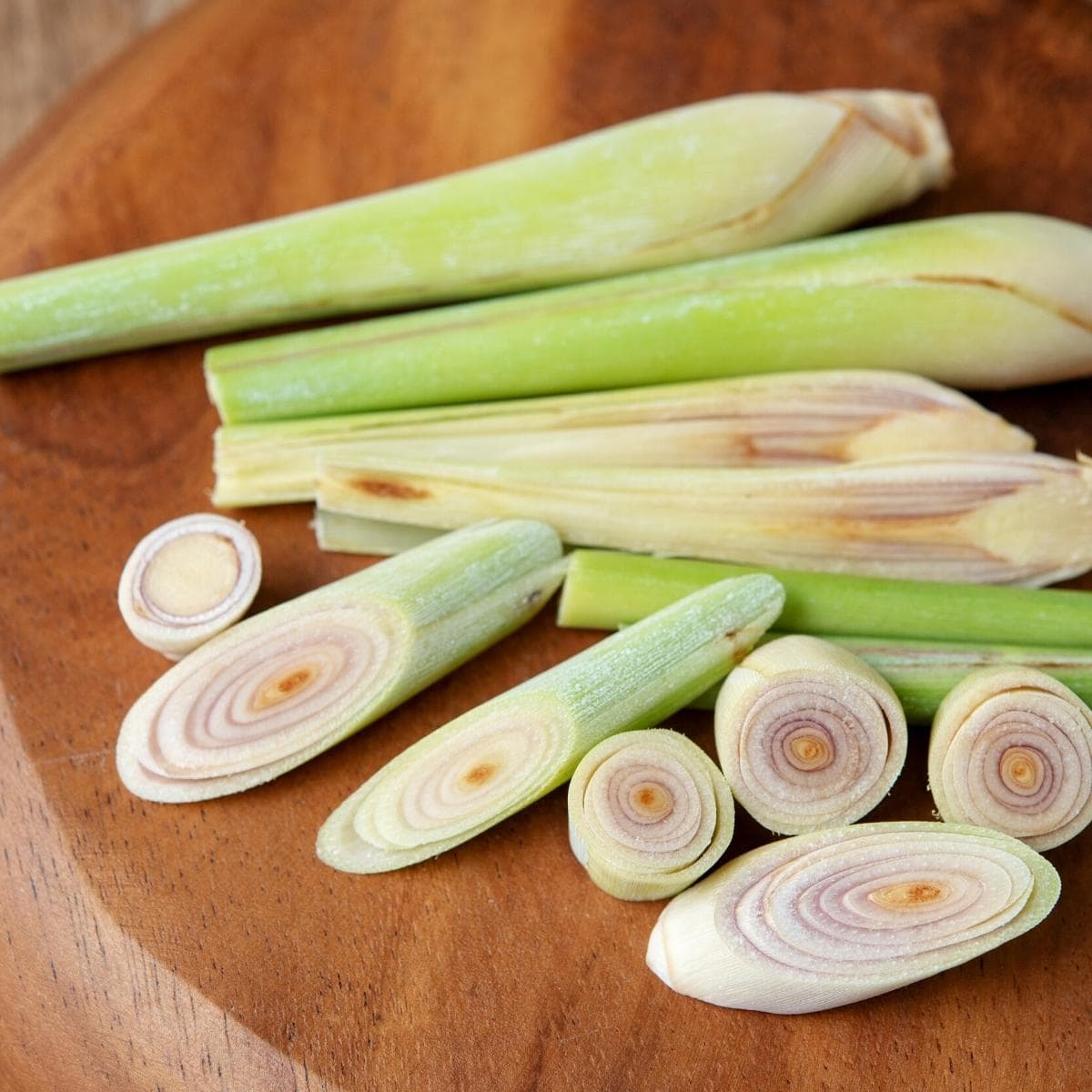 Sliced lemongrass resting on a wooden cutting board.