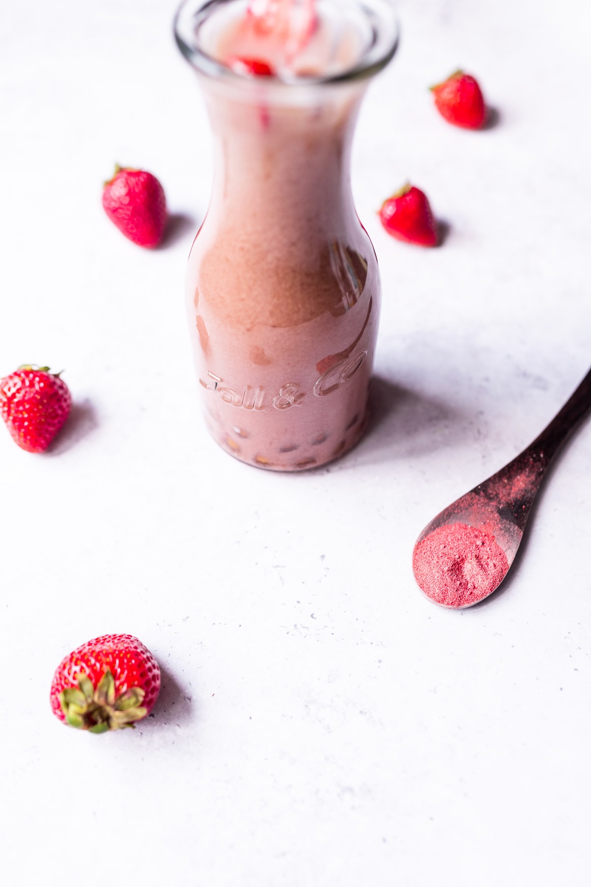 A tall glass bottle filled with strawberry milk tea.