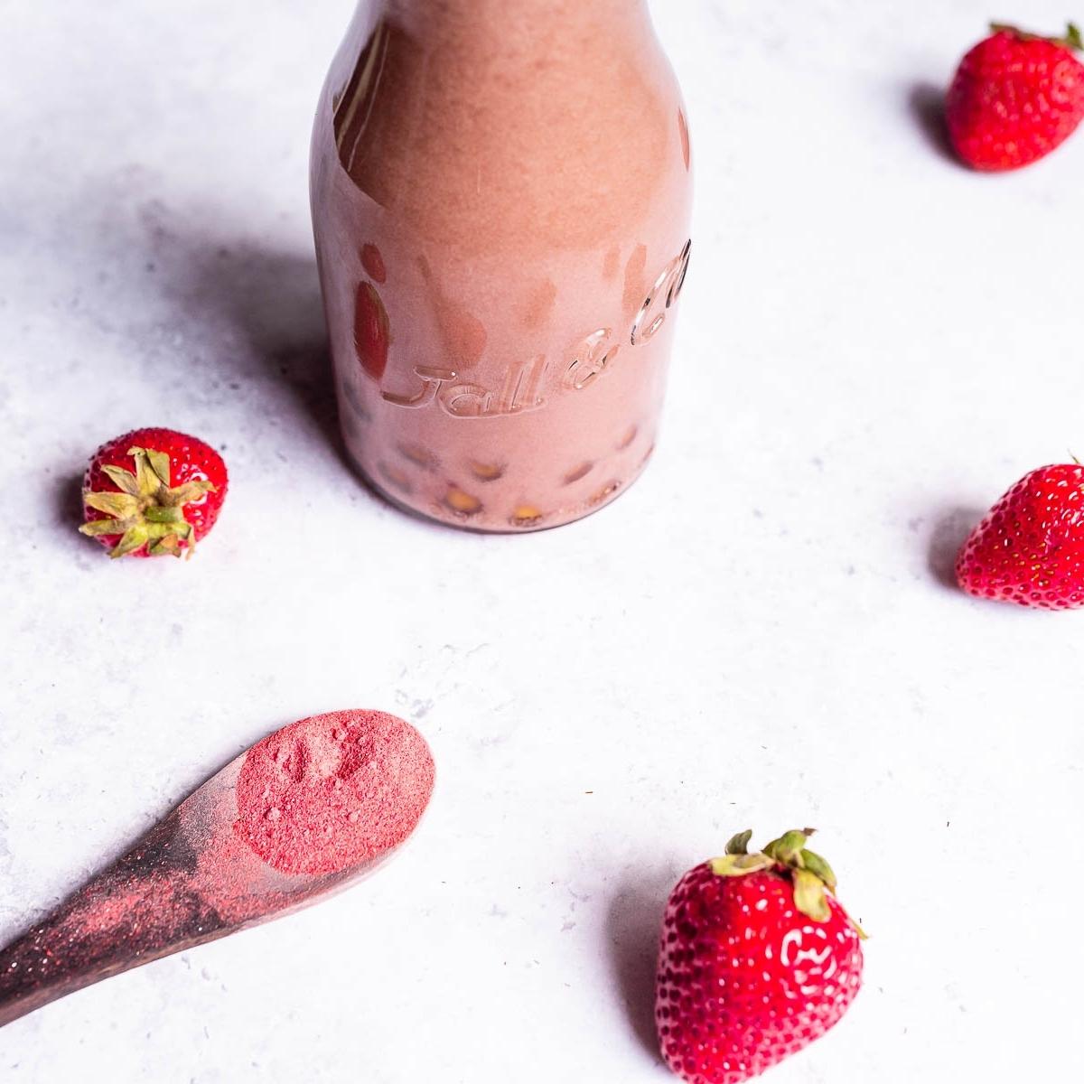 A clear glass bottle filled with a pink liquid and brown tapioca pearls.