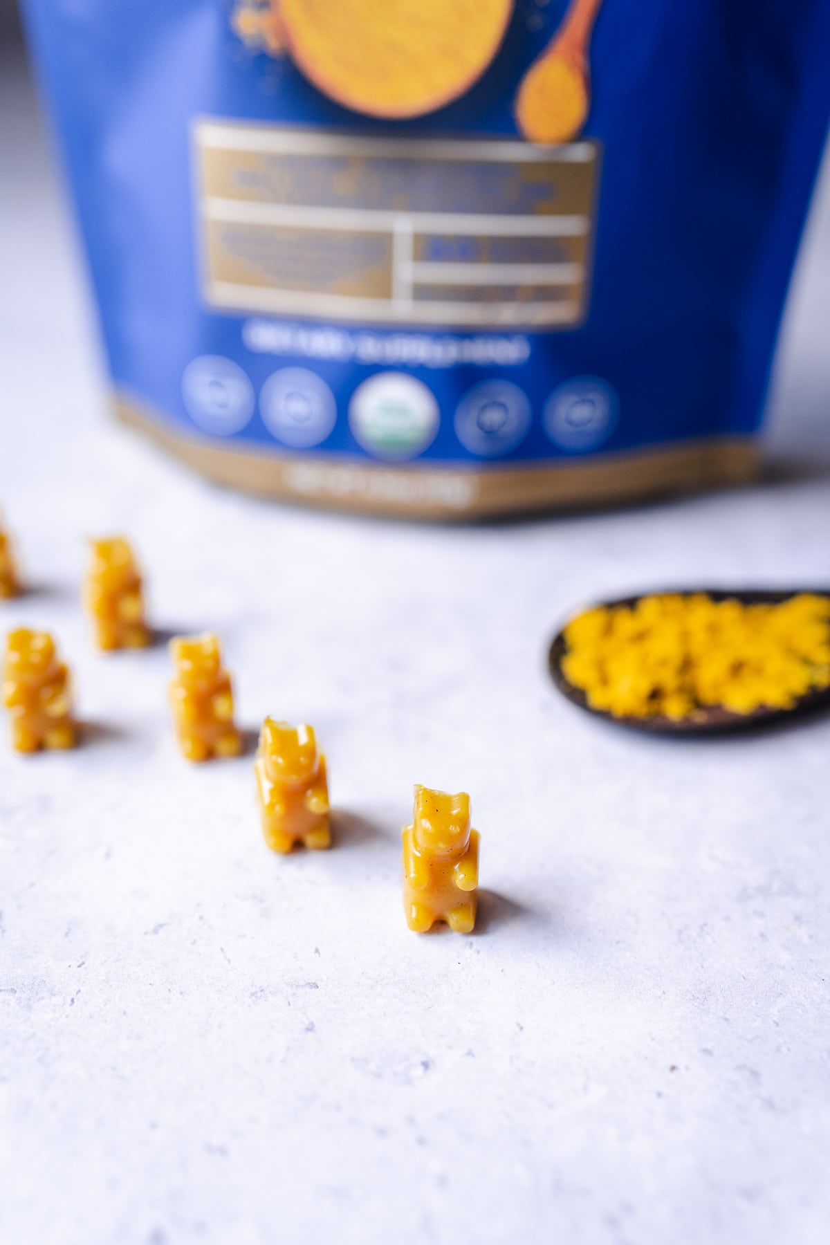 Small yellow vegan gummy bears standing up in a row.