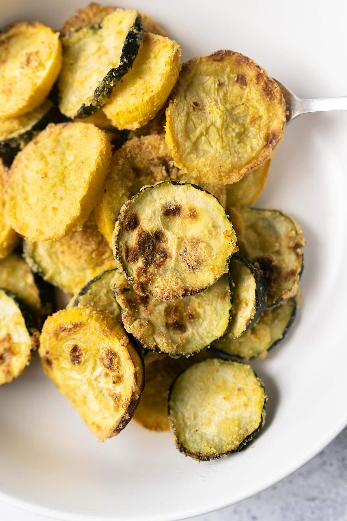 Close shot of crispy squash slices in a white bowl.