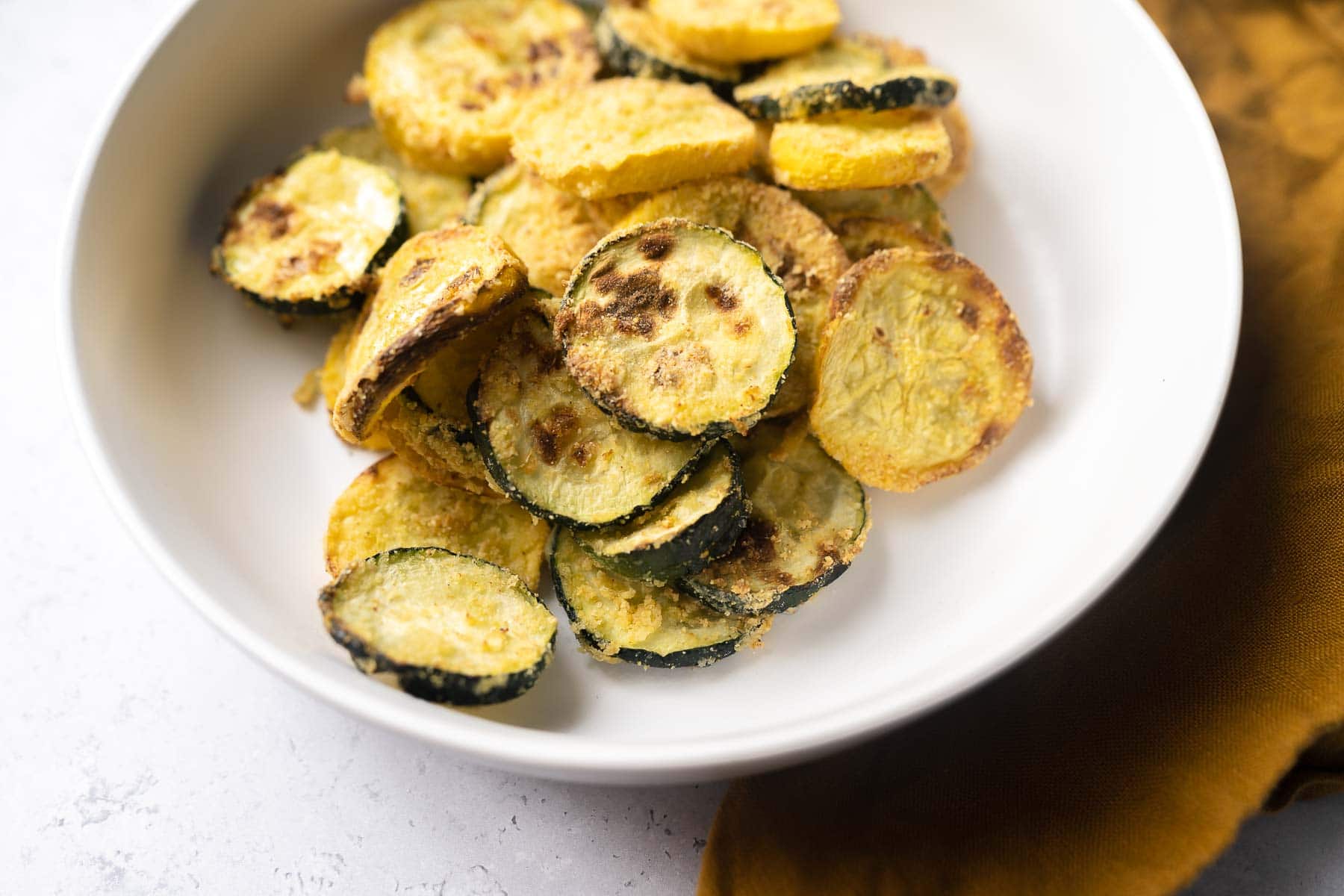 A small white bowl filled with browned sliced squash pieces.