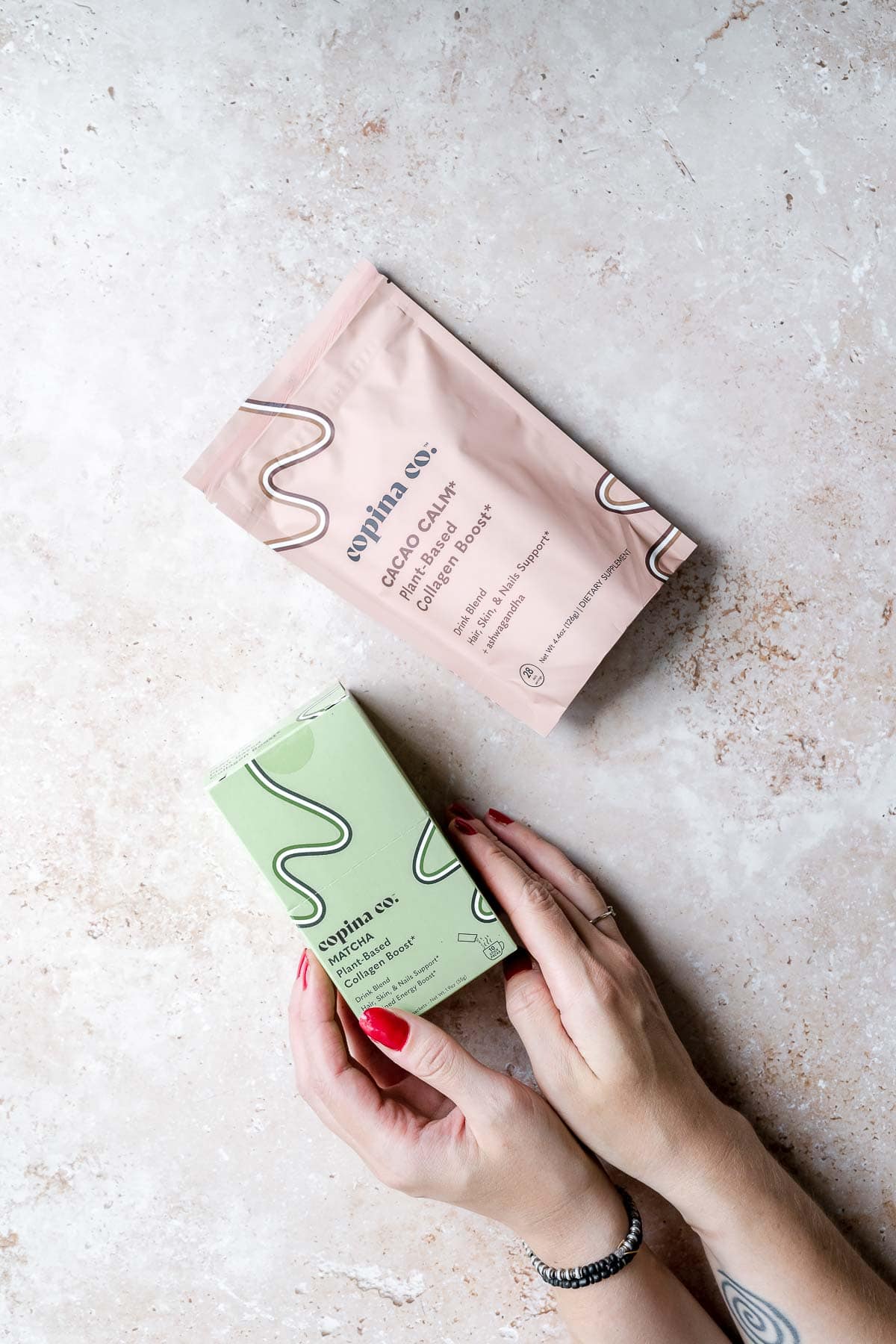 Hands holding a green box of copina co. match plant based collagen boost.