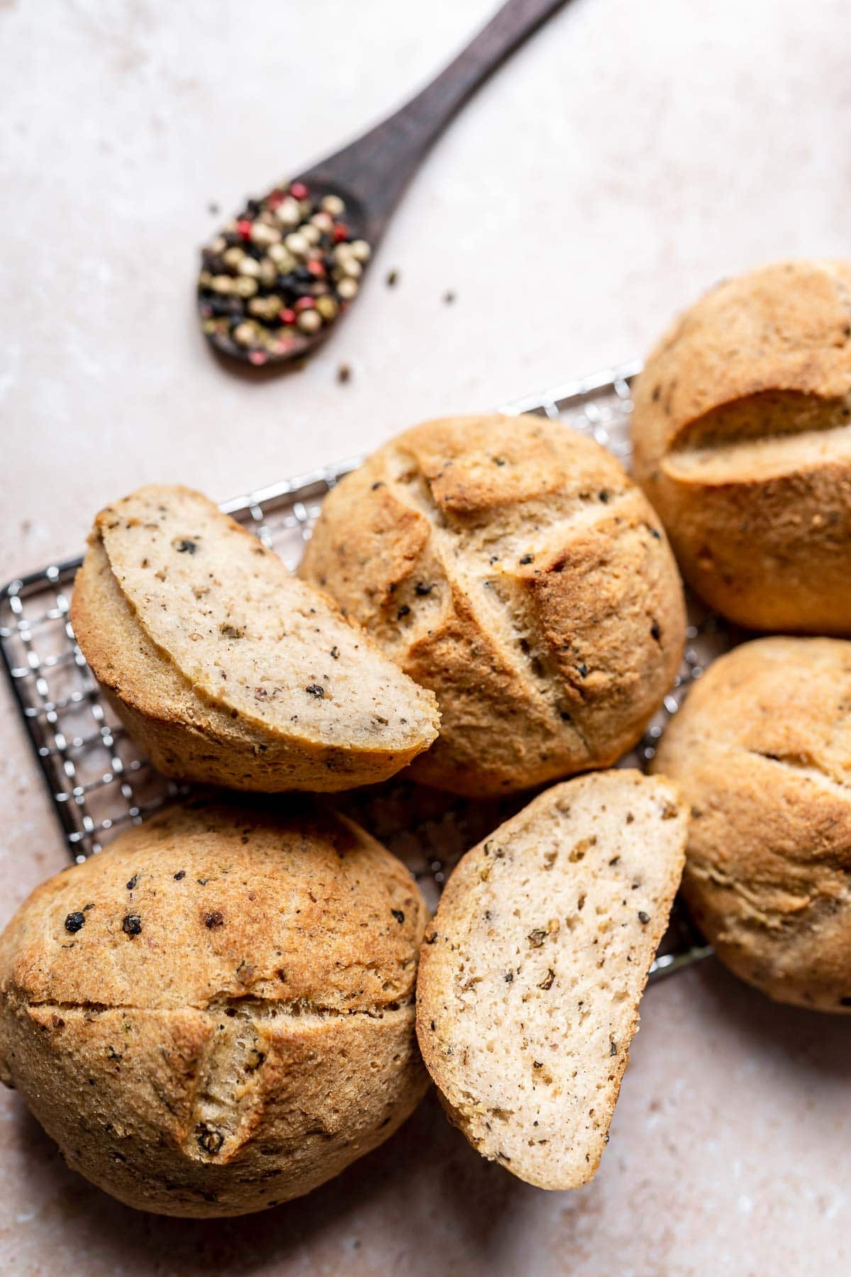 Golden bread rolls, some whole, some sliced, resting a silver metal cooling rack.