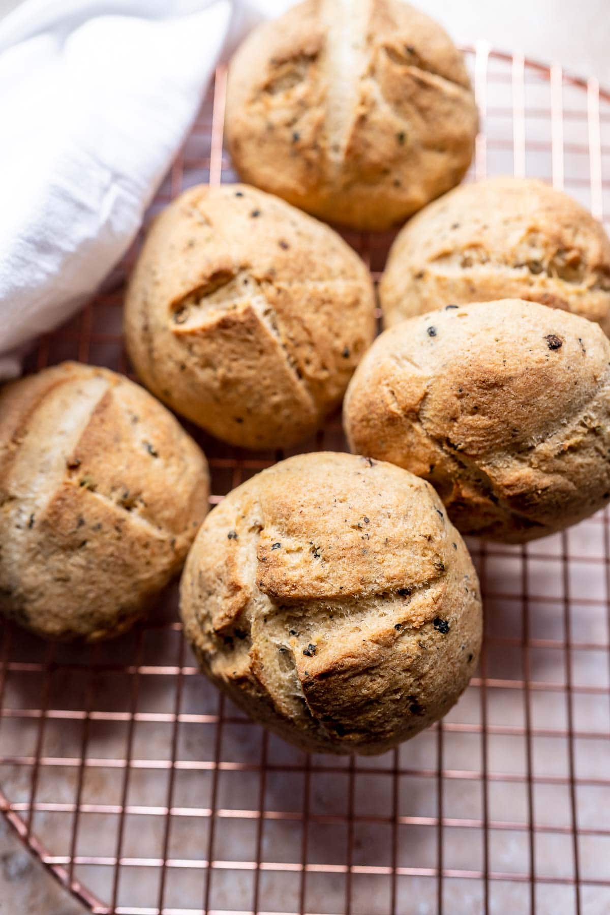 A pile of sourdough rolls resting on a cooling rack.