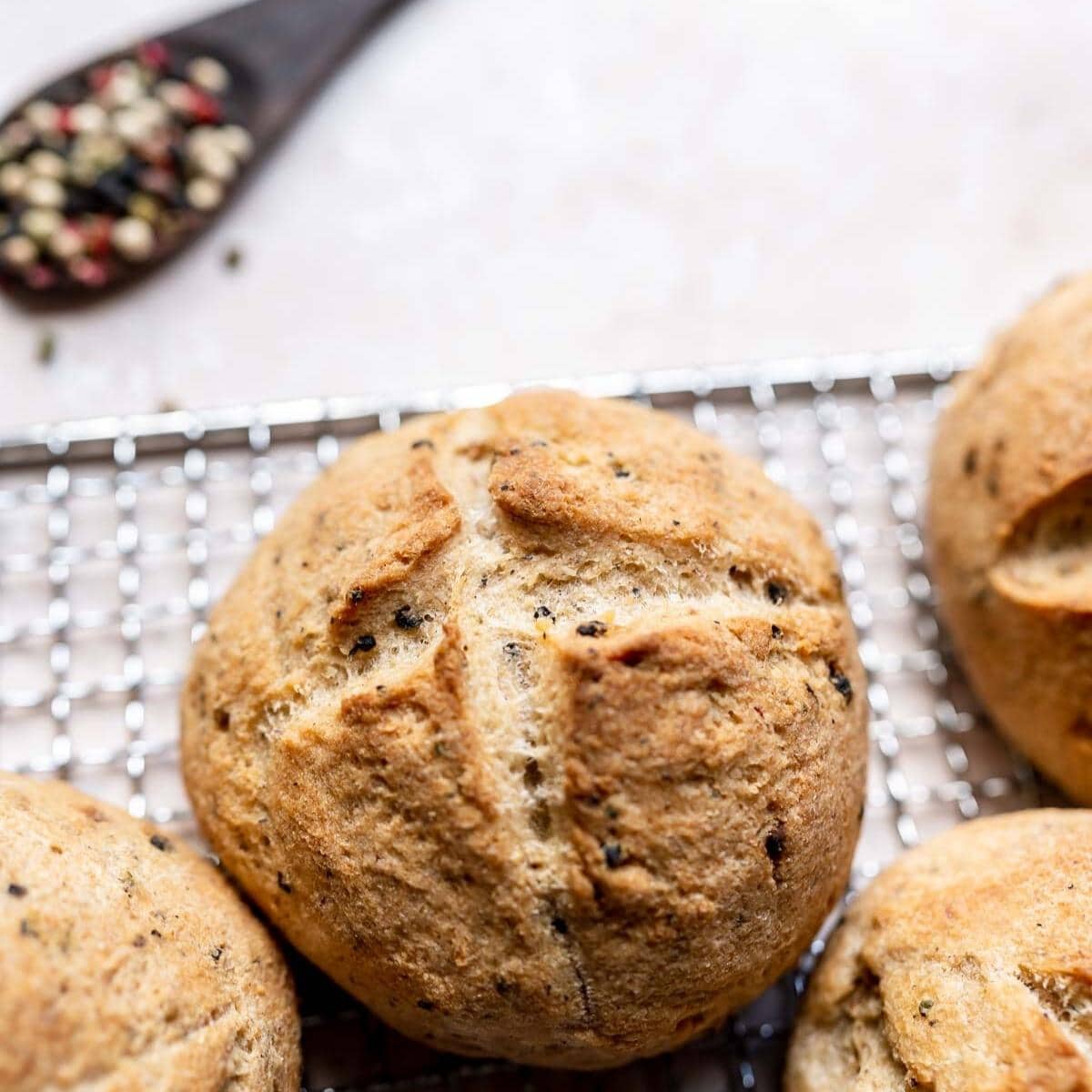 A close shot of a bread with a golden crust speckled with black peppercorns.