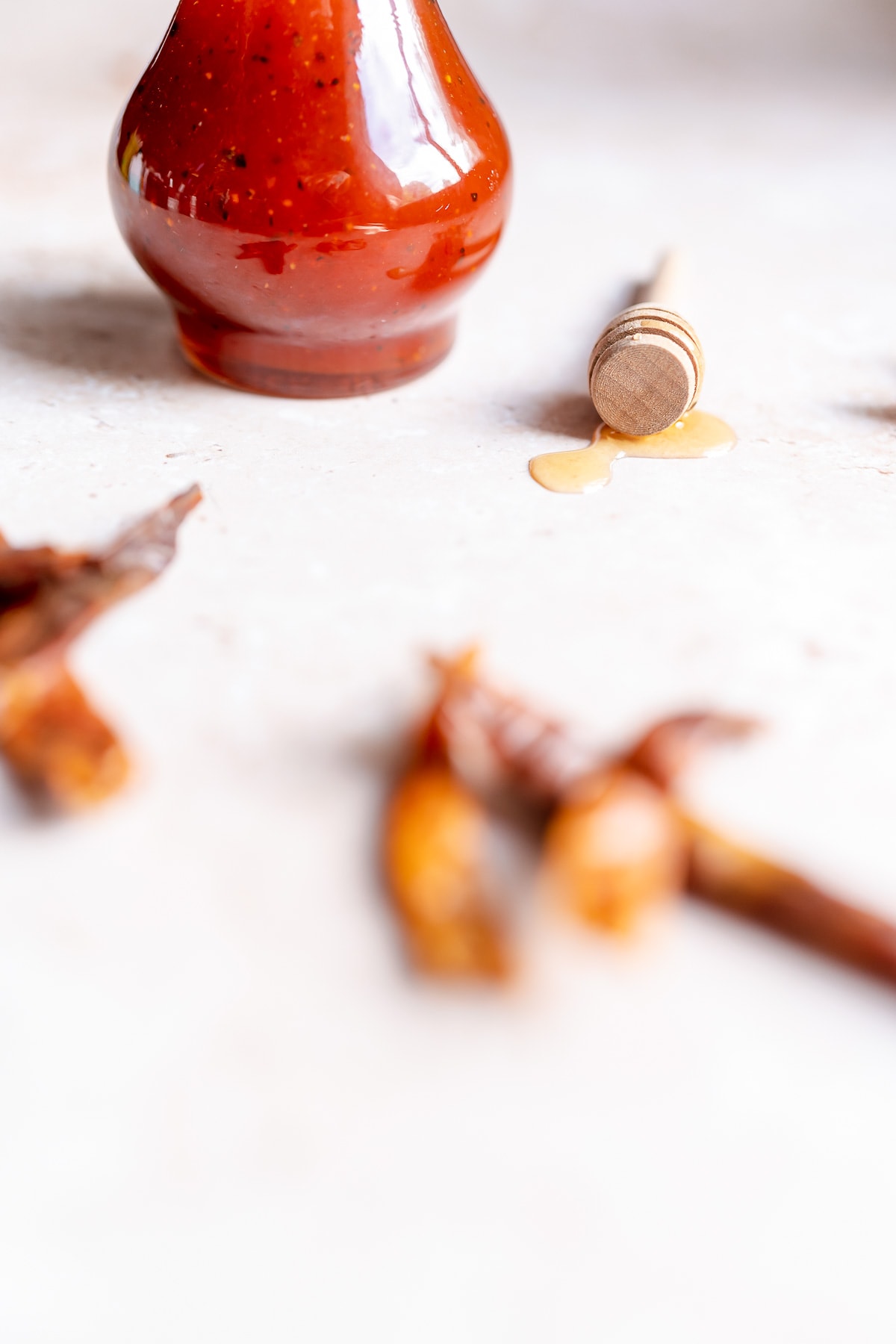 Close shot of a clear glass bottle filled with a bright red sauce.