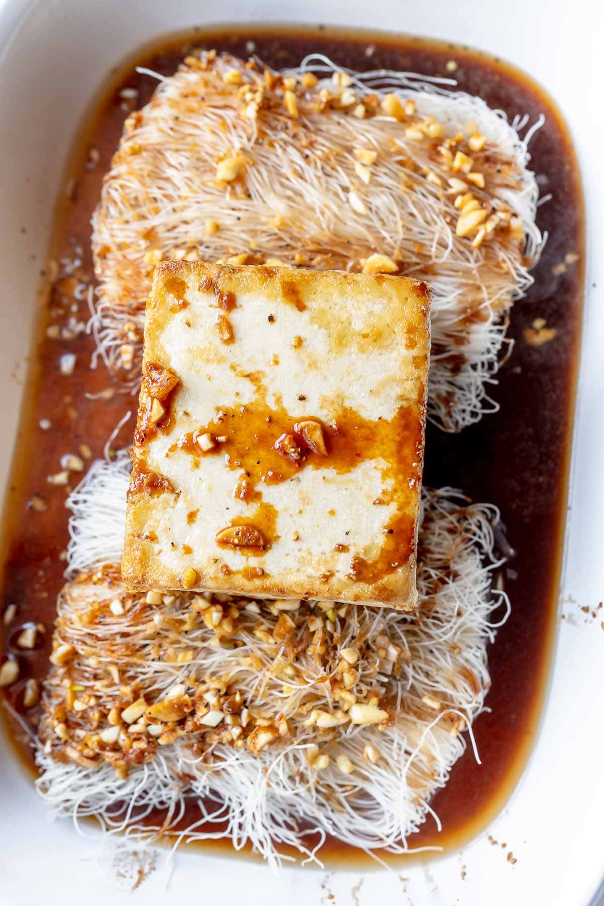 Tofu, noodles and sauce sitting in a white baking dish.