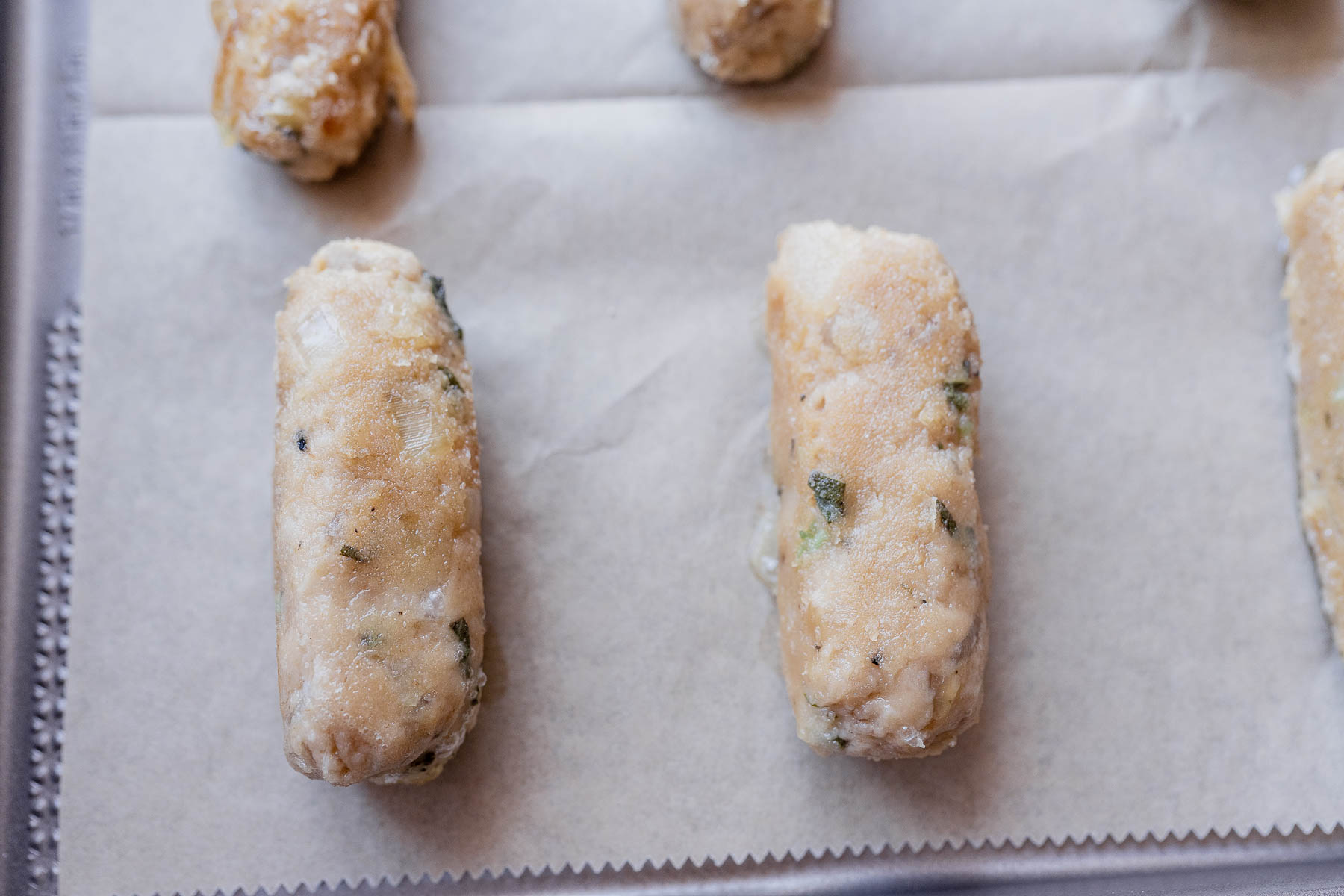 A baking sheet with parchment paper and sausage rolls.