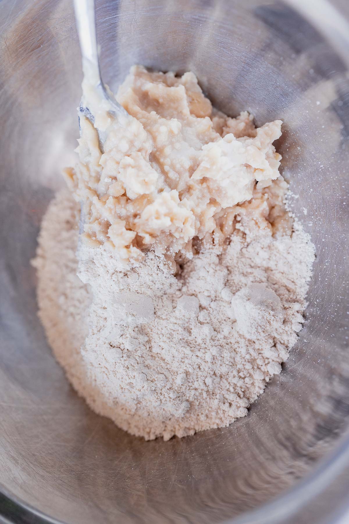 A silver bowl filled with mashed beans and flour.