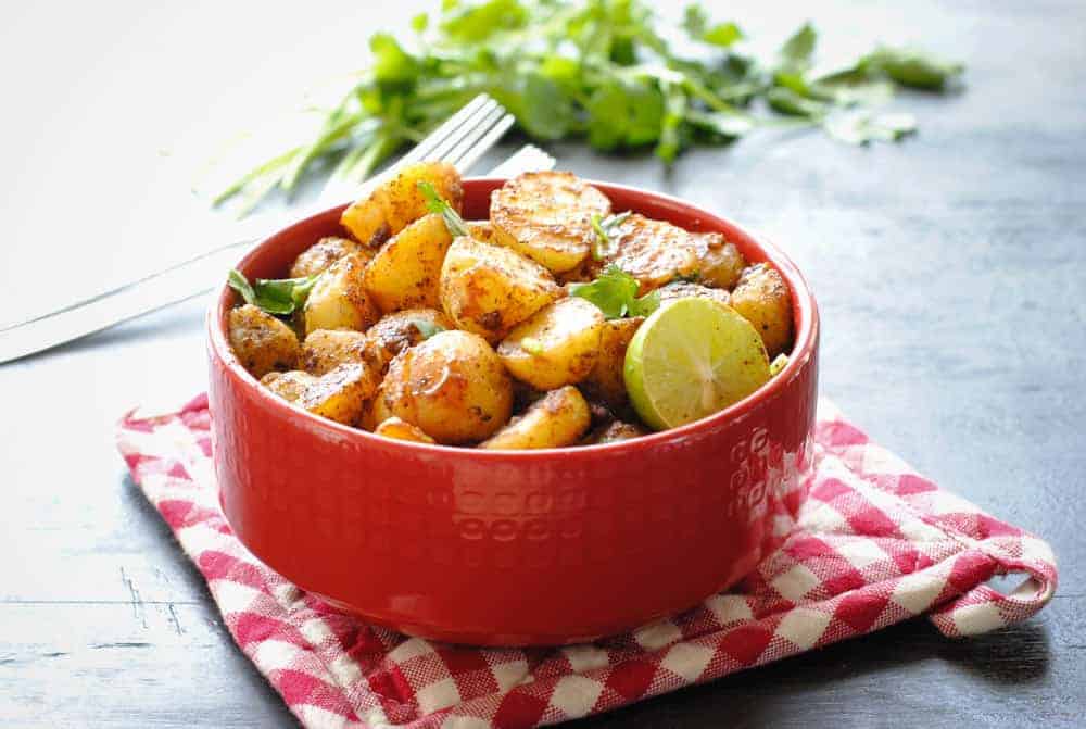 The Indian dish aloo chaat in a red ceramic bowl.