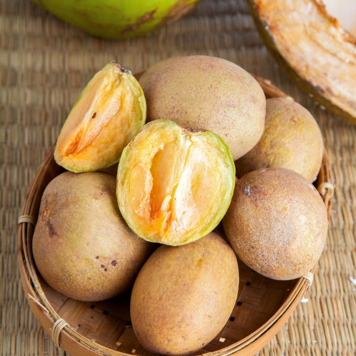 A pile of sapodilla fruit resting in a wooden basket.