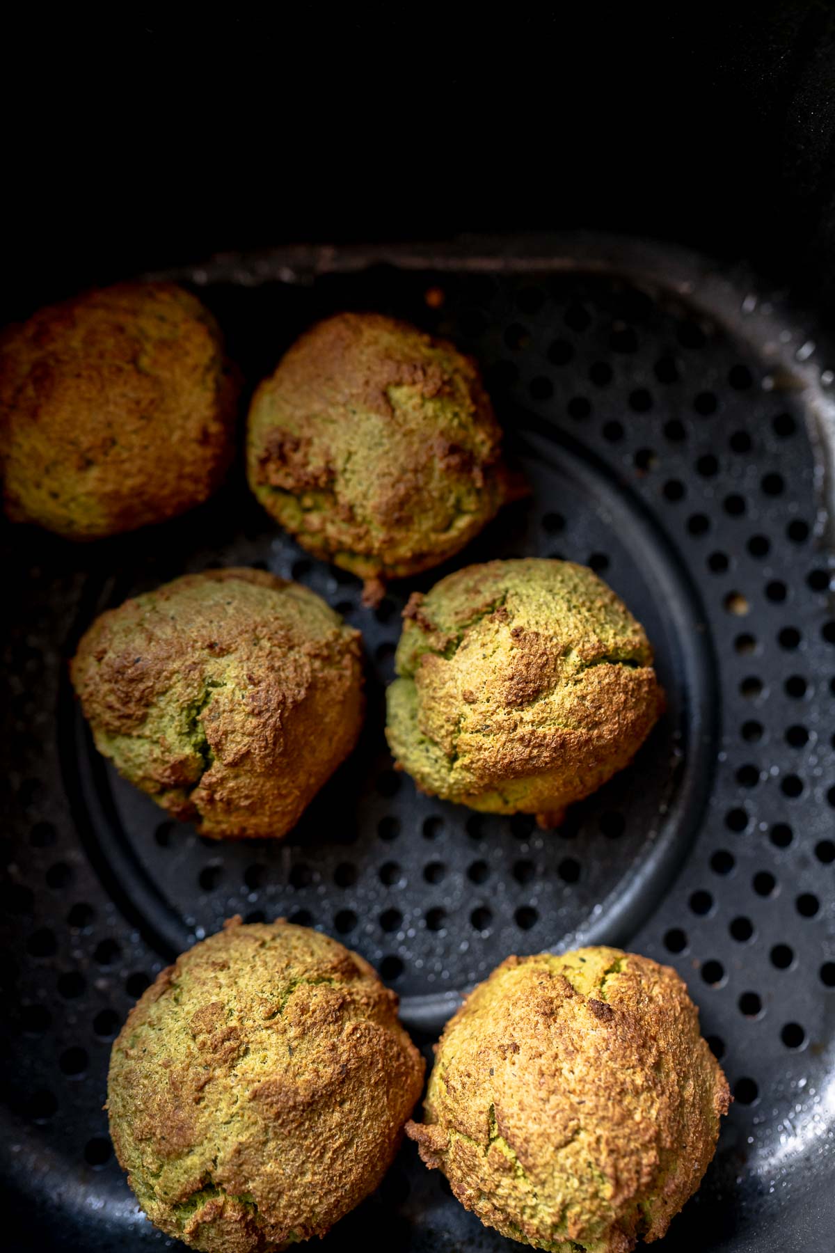 Crispy golden falafel balls resting in a black air fryer basket.