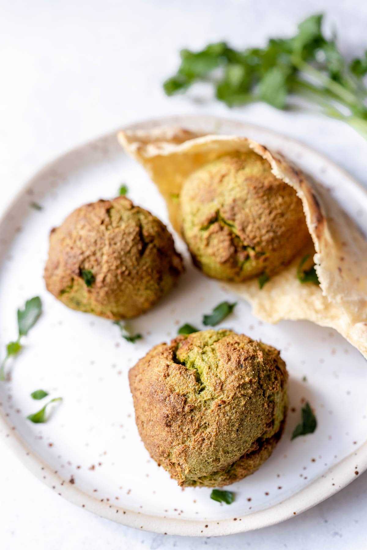 A white speckled ceramic plate topped with brown falafel balls.