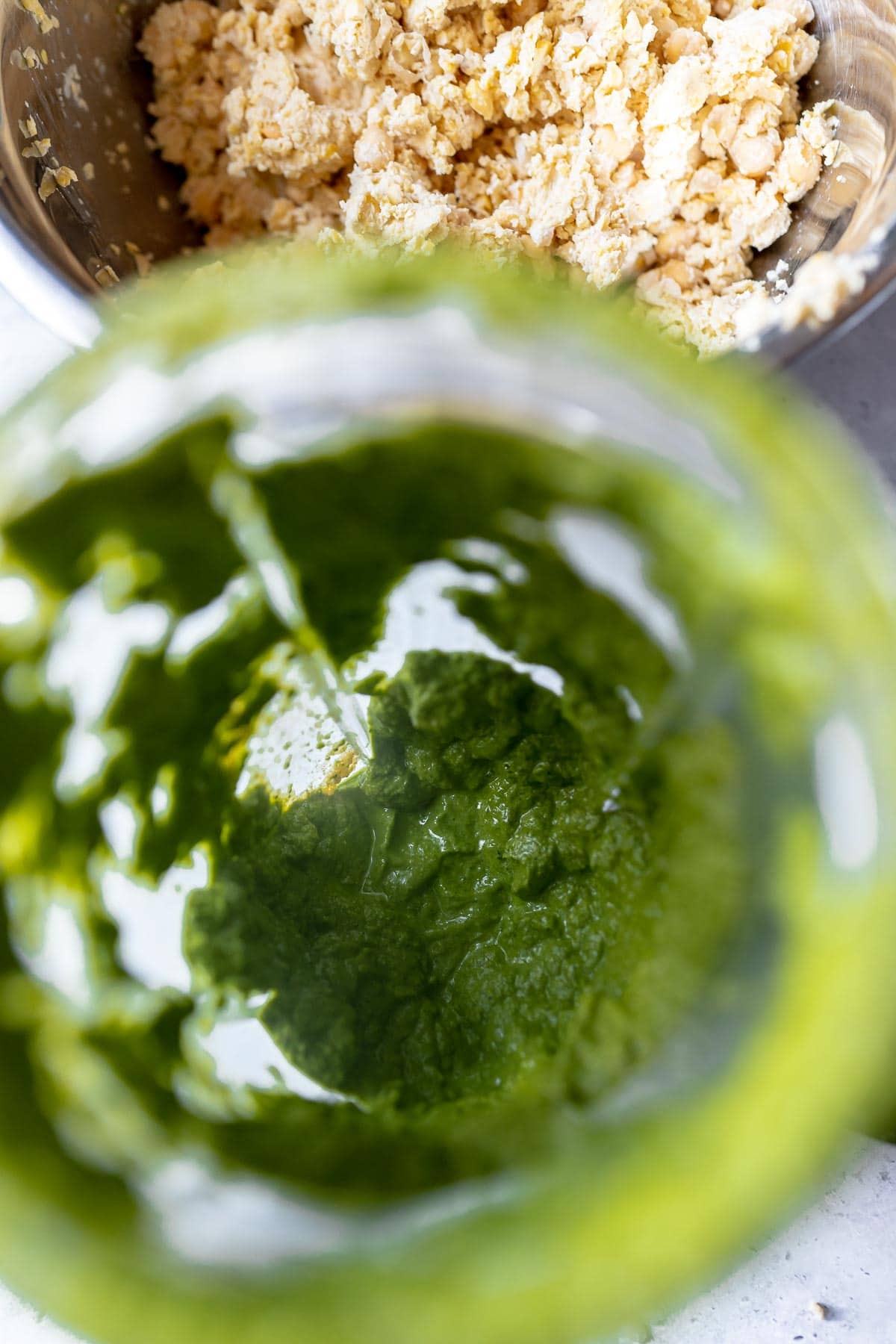 A clear plastic blender container filled with green batter.