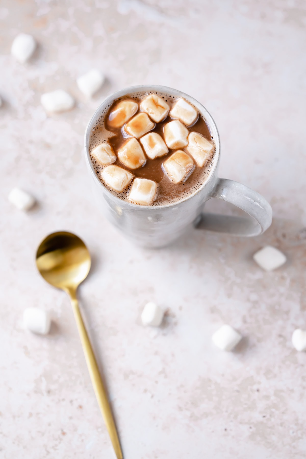 A white mug filled with hot cocoa and small marshmallows.