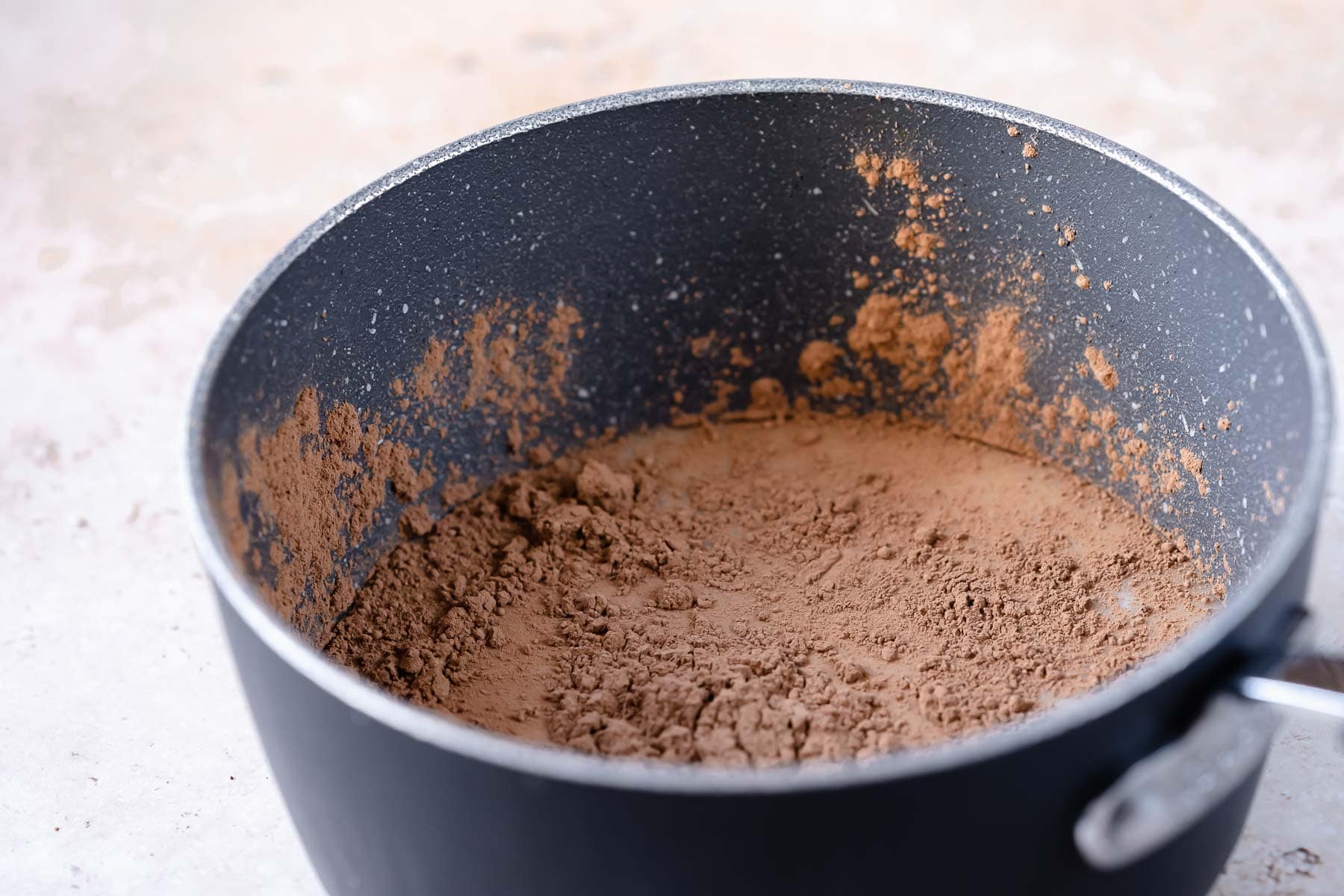 A dark gray saucepan filled with brown powder.
