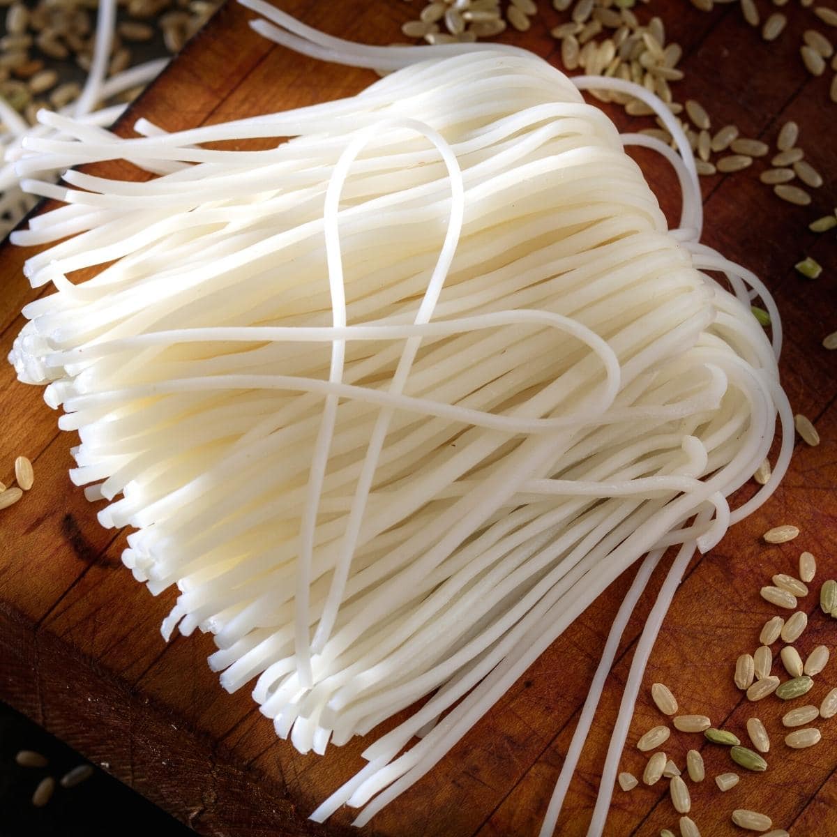 Dry white rice noodles resting on a wooden table.