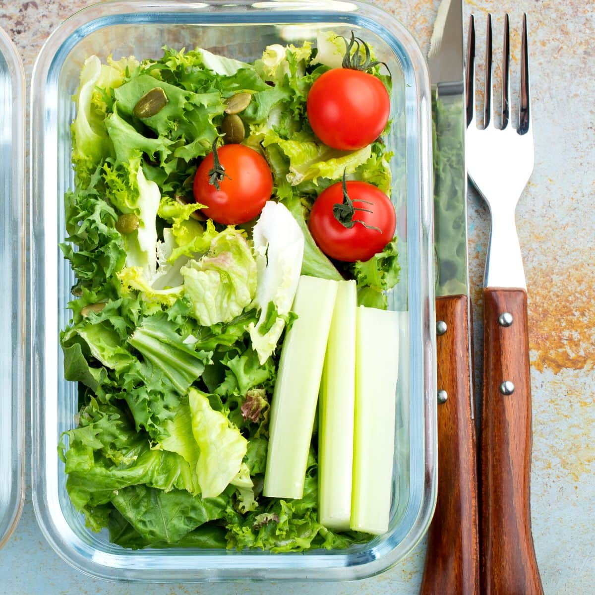 An open glass storage container filled with salad.