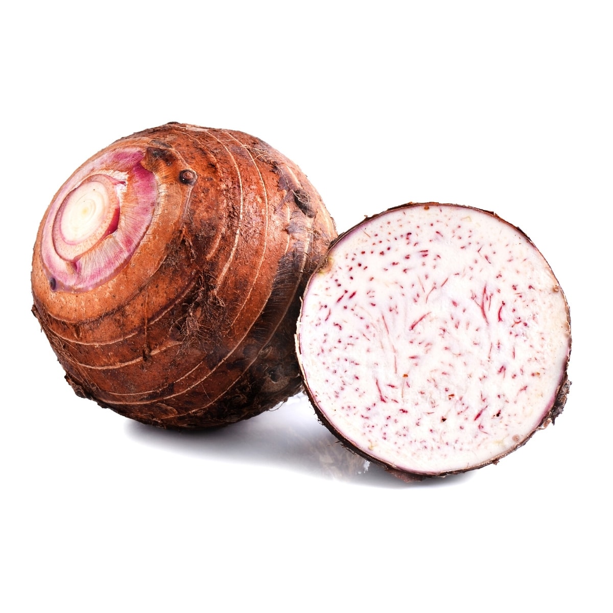 Freshly cut taro root on a white table, displaying its white flesh with purple dots.