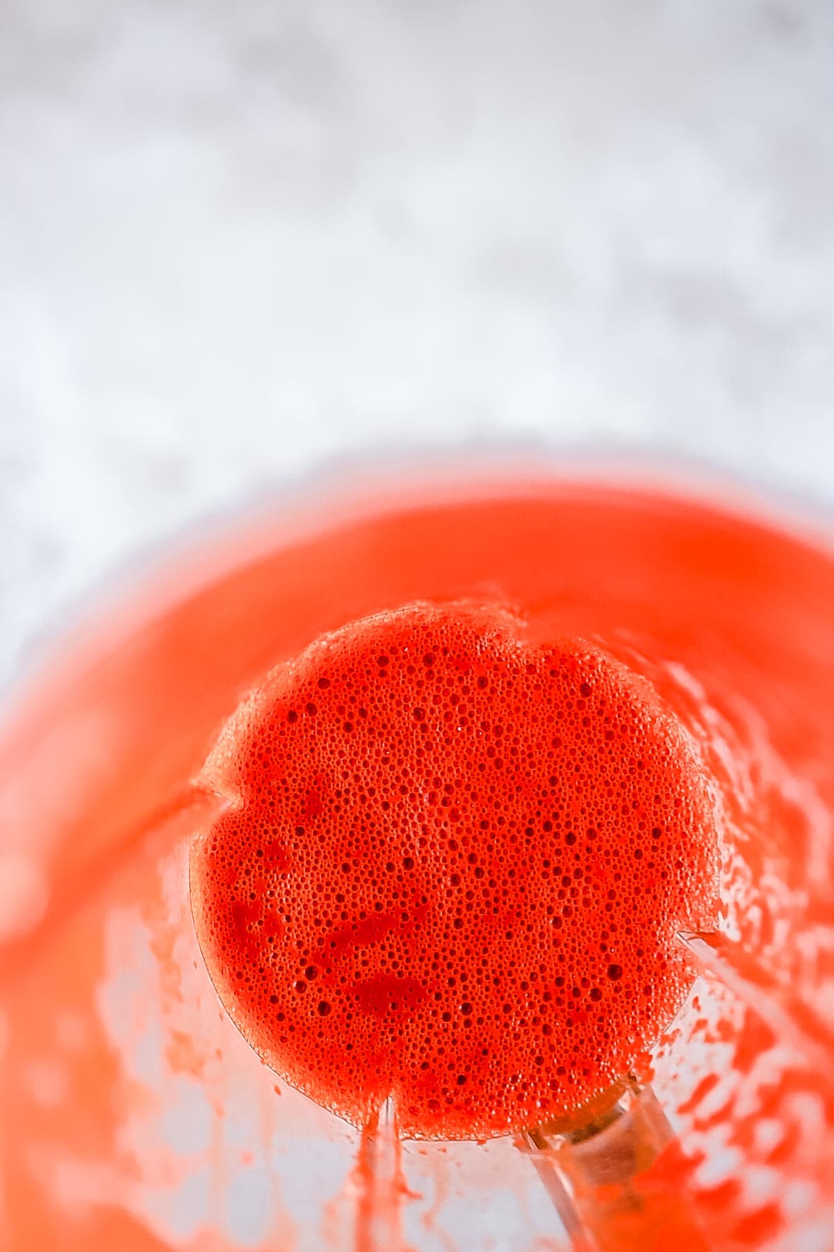 A close shot of the contents of a blender cup filled with a bright red sauce.