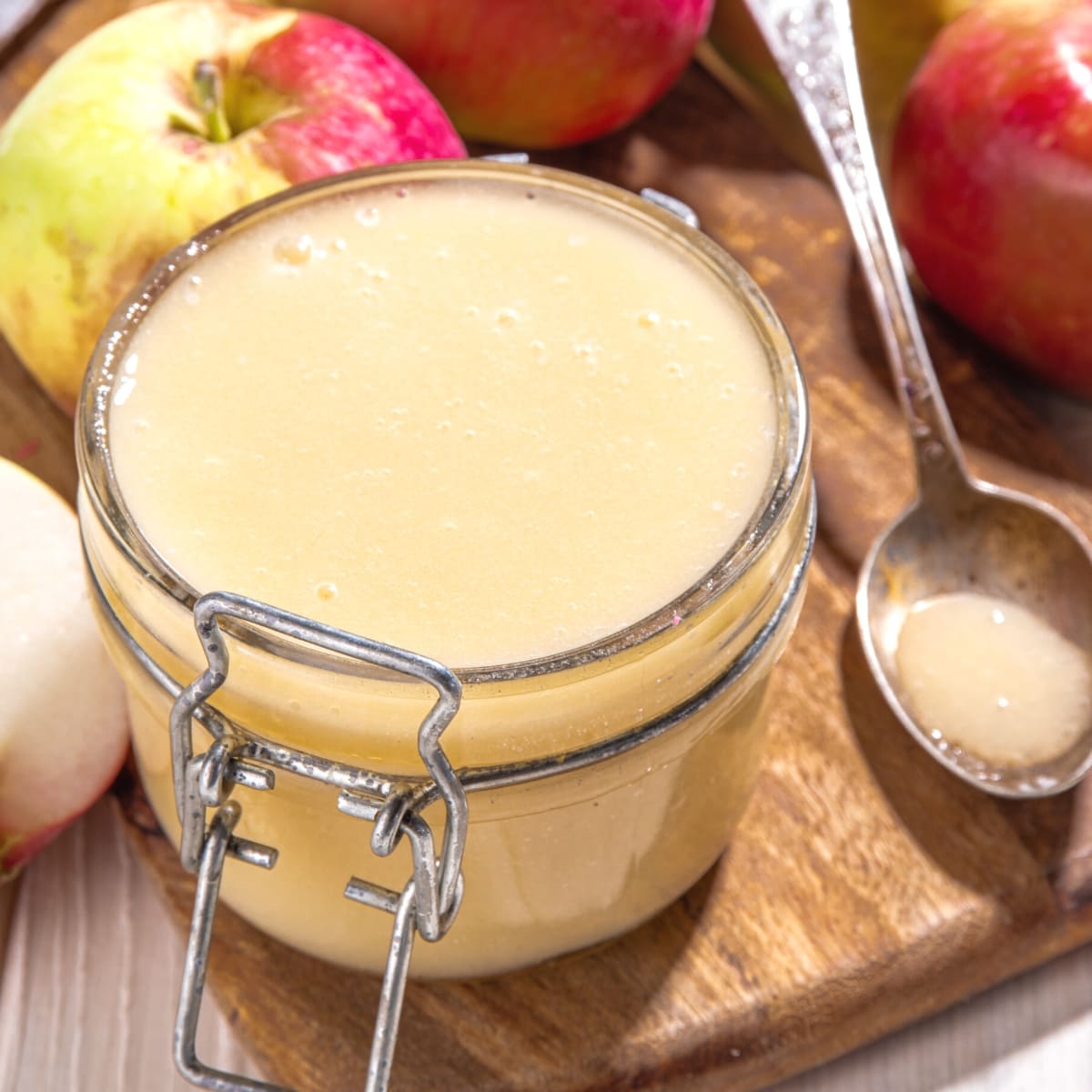 A clear glass jar filled with apple sauce.
