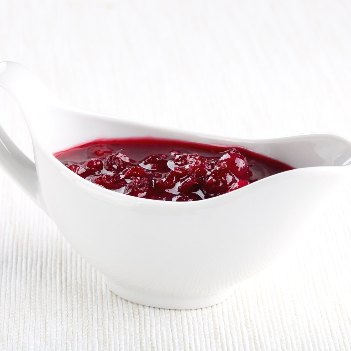 A white ceramic container filled with red cranberry sauce.