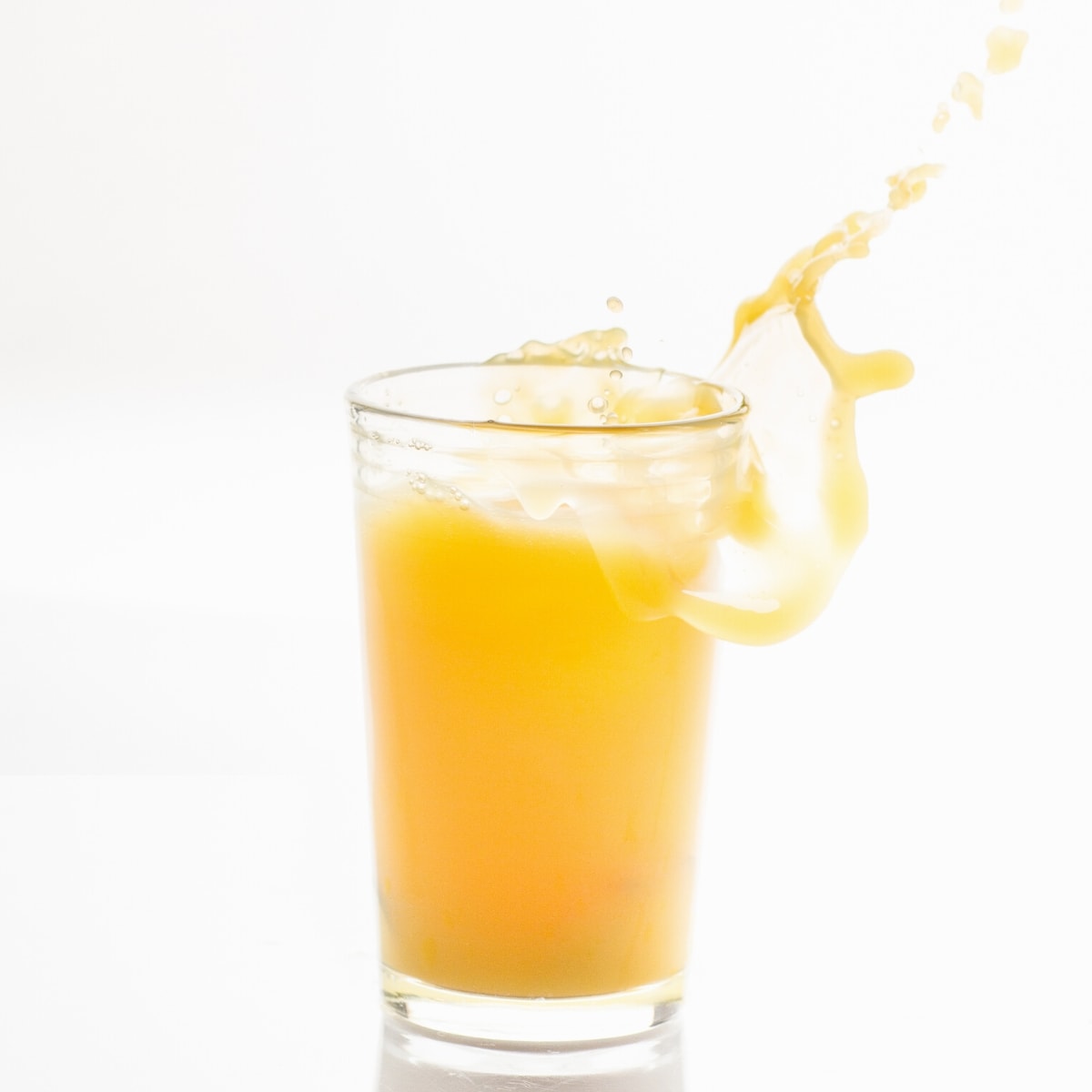 A tall clear glass filled with orange juice.