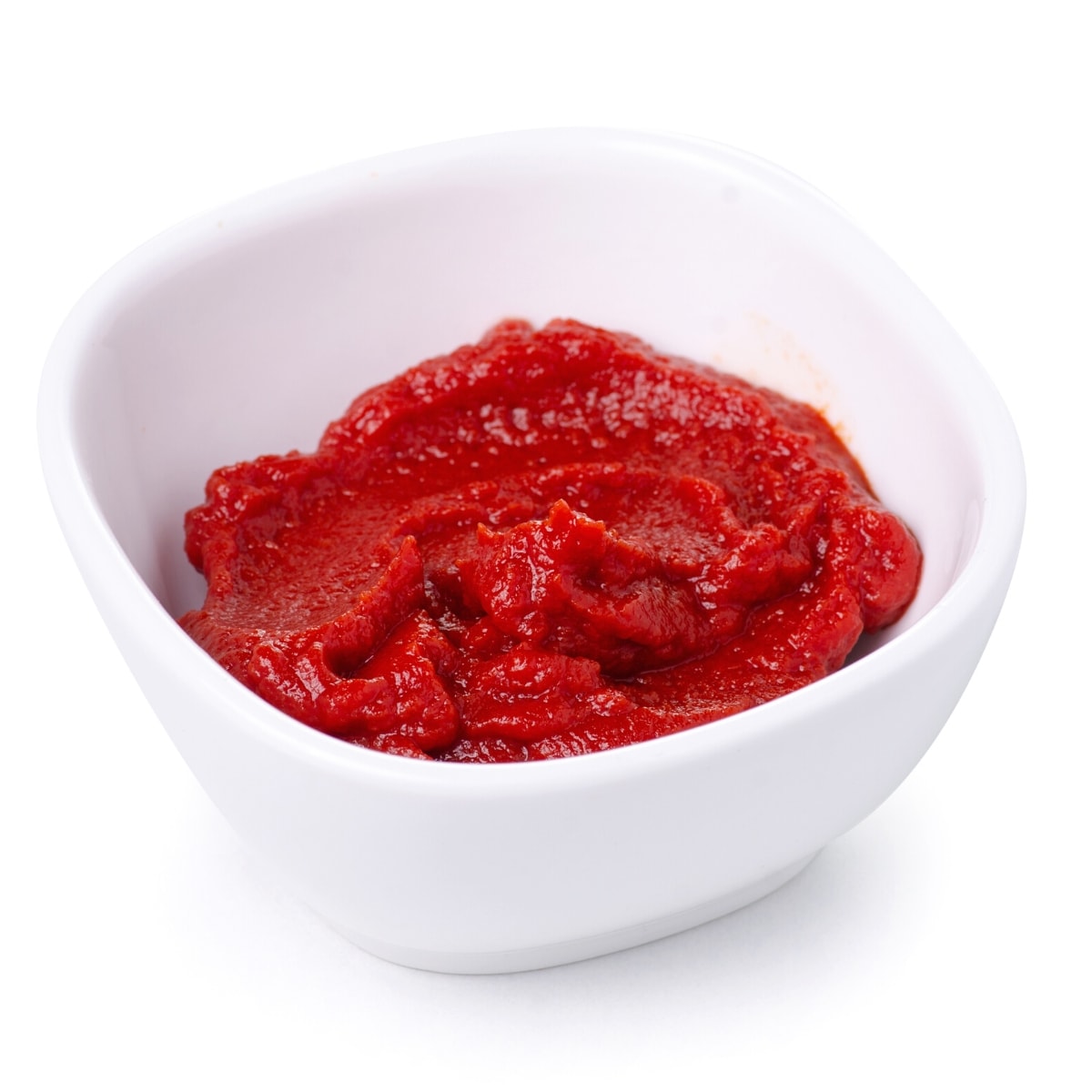 A white ceramic bowl filled with thick red tomato paste.
