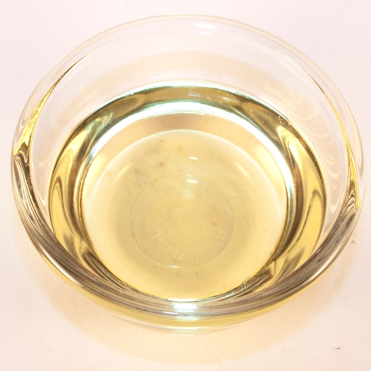 A clear glass bowl filled with white wine vinegar.