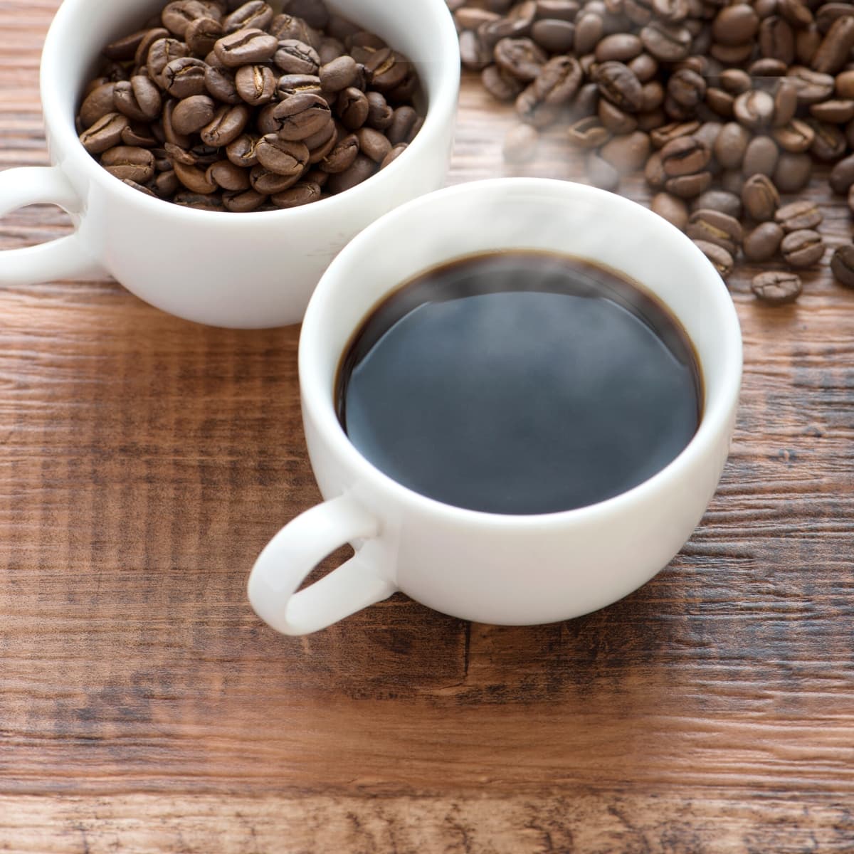 Two white ceramic mugs filled with black ivory coffee.