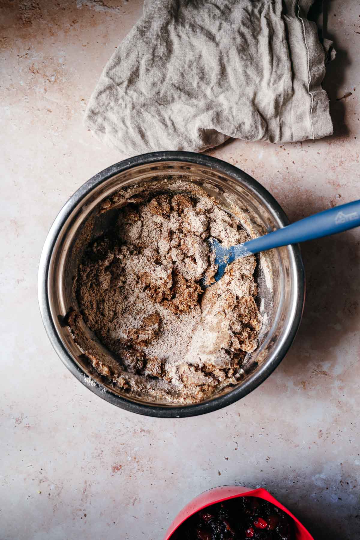 A cake batter being mixed in a silver mixing bowl with a blue spatula.