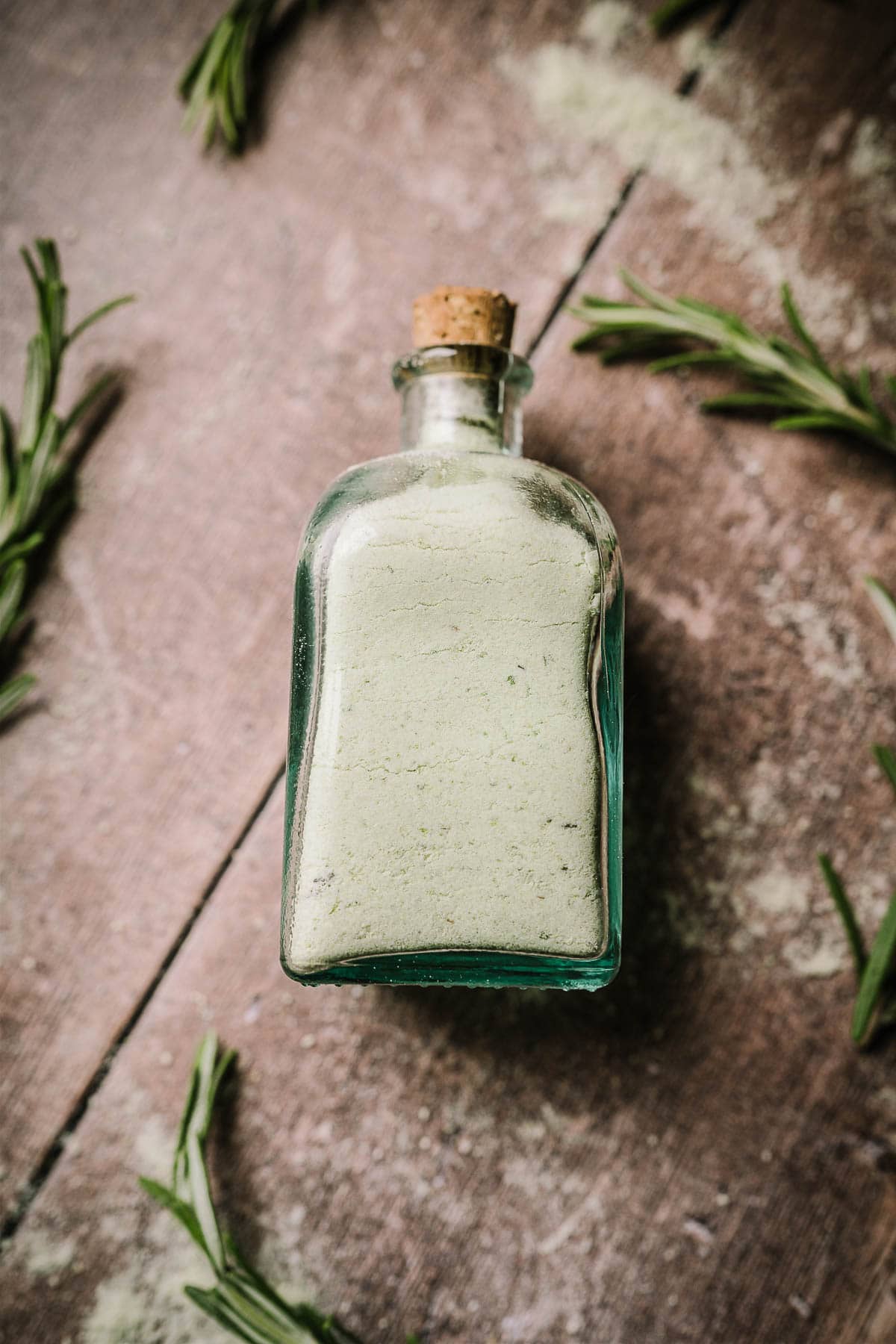Close shot of clear corked glass bottle filled with green salt.