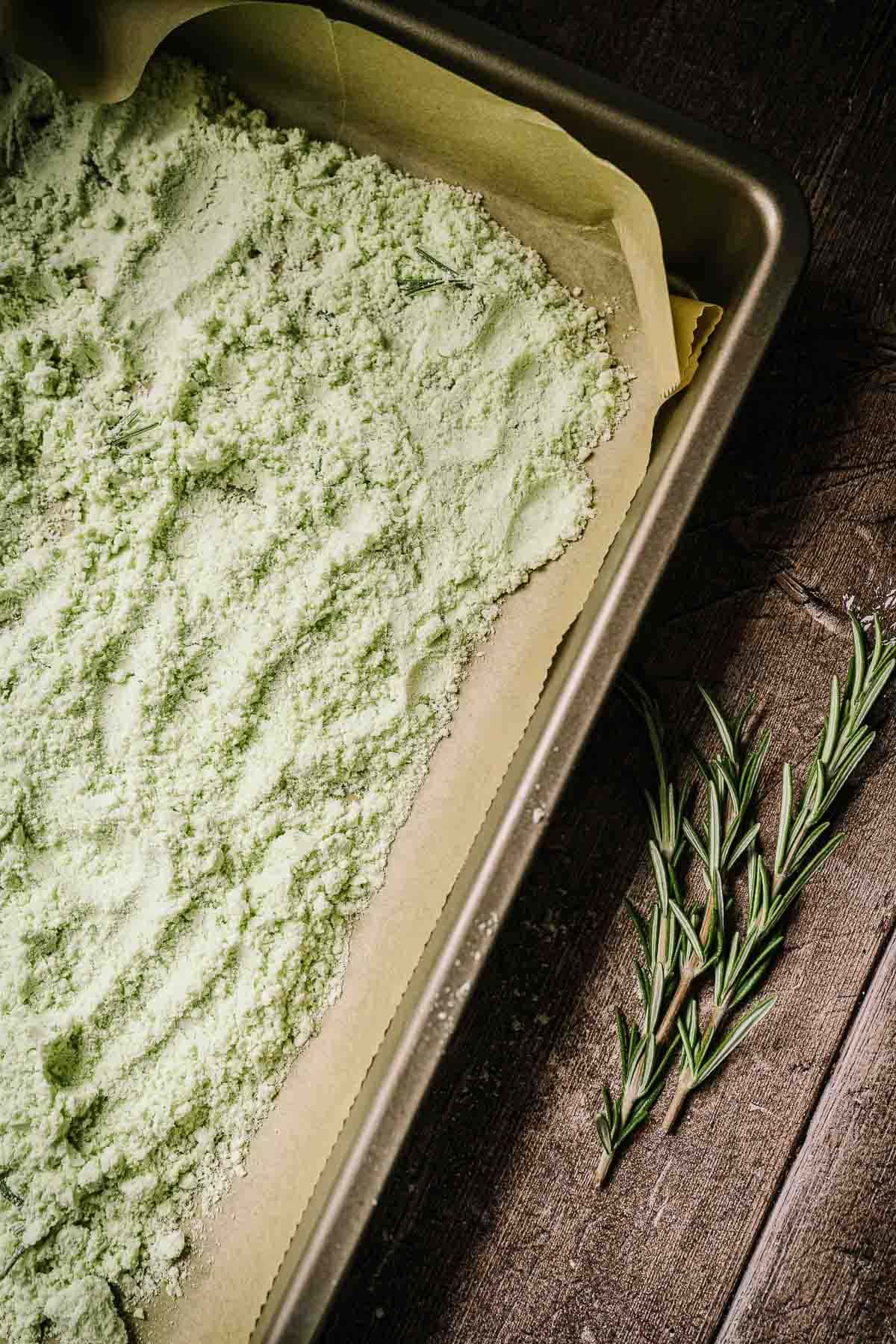 A baking sheet filled with fine green salt.